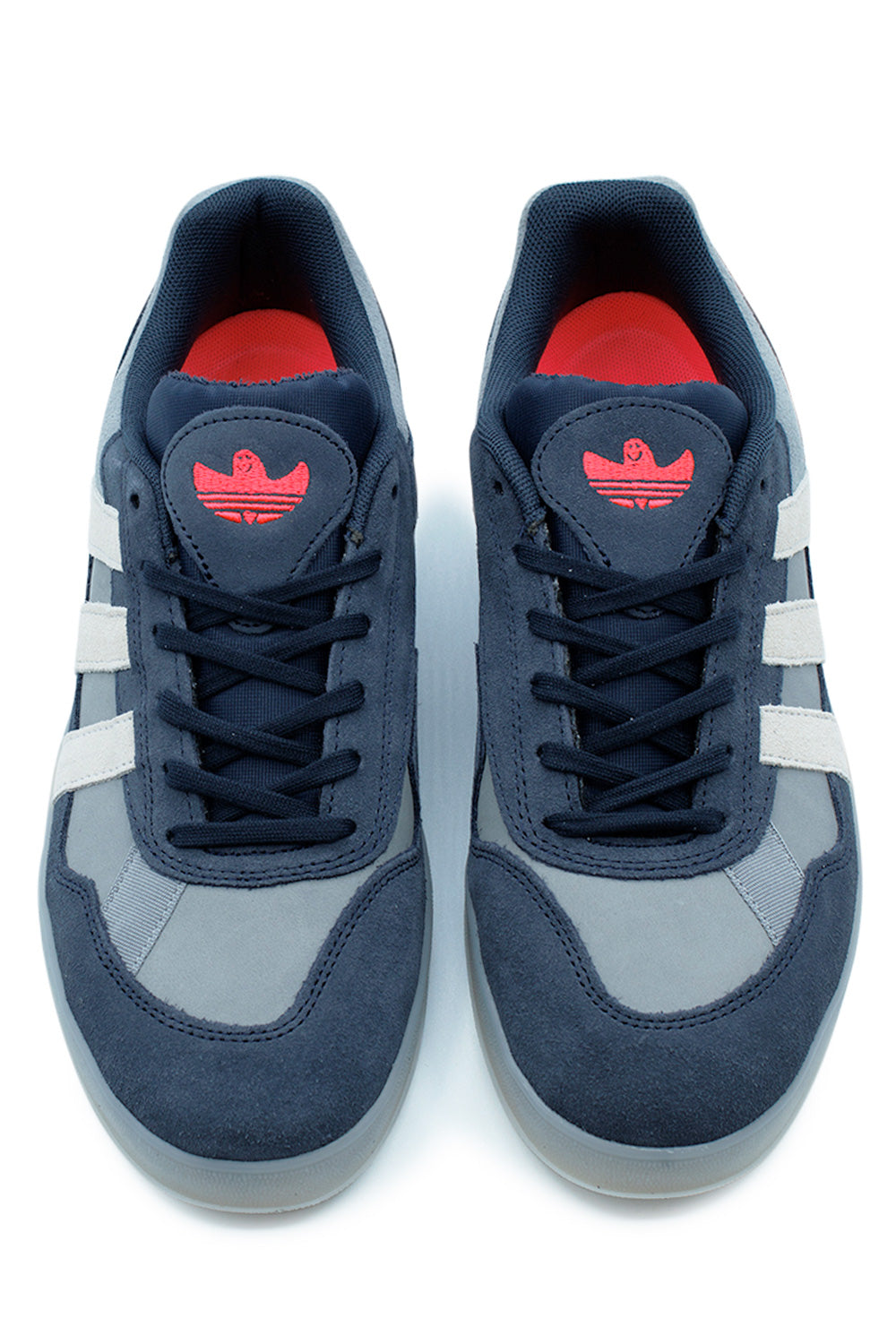 Top-down view of a pair of adidas Aloha Super sneakers, highlighting the dark navy laces and the bright red embroidered Shmoo Trefoil logo on the tongues.