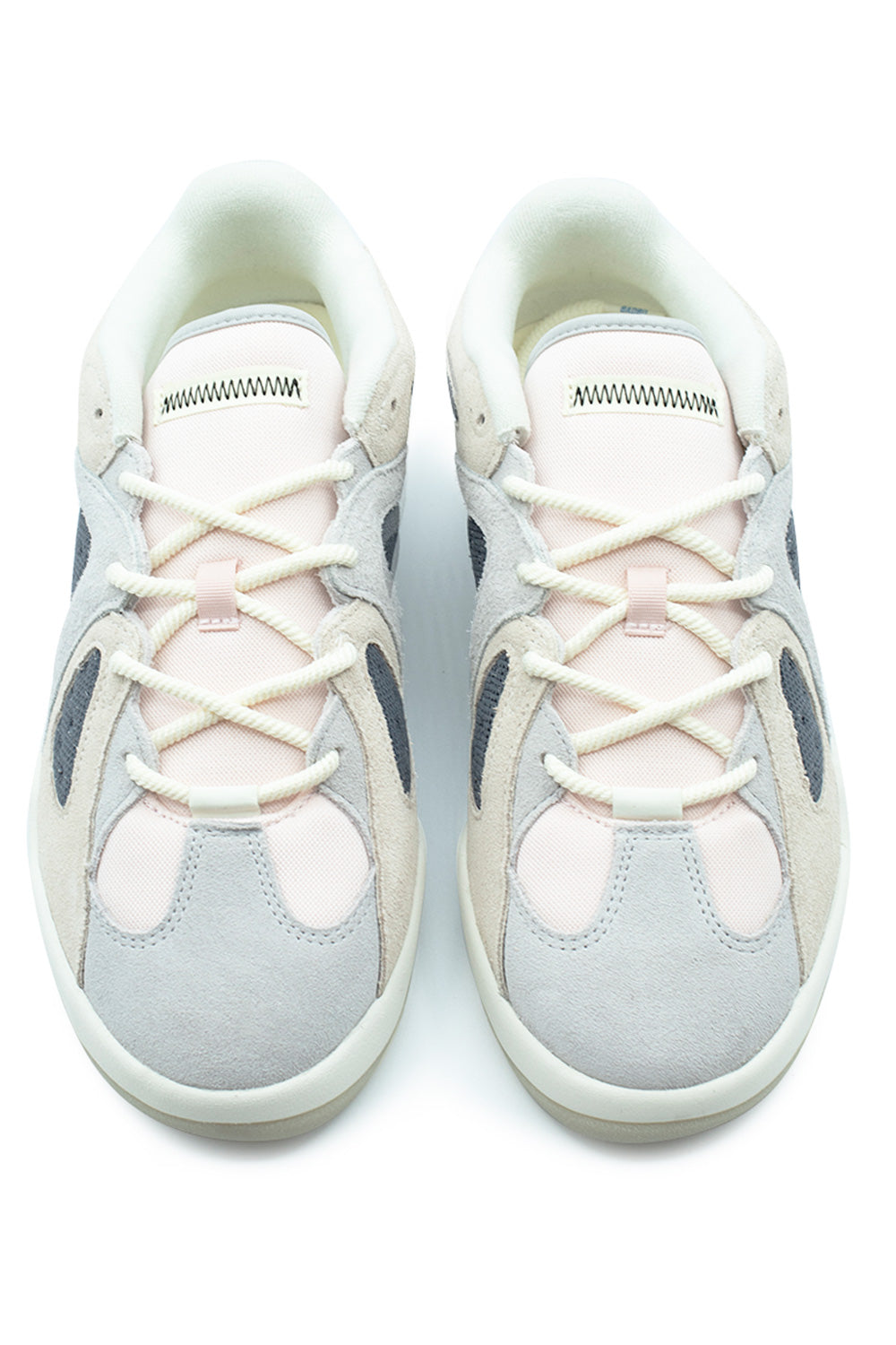 Top-down studio view of a pair of Adidas Bad Bo 1.1 skate shoes, highlighting the light grey suede toe caps, pastel pink canvas toe box panels, off-white round cord laces threaded through ghillie loops, and plush padded pale pink tongues detailed with black zig-zag contrast topstitching