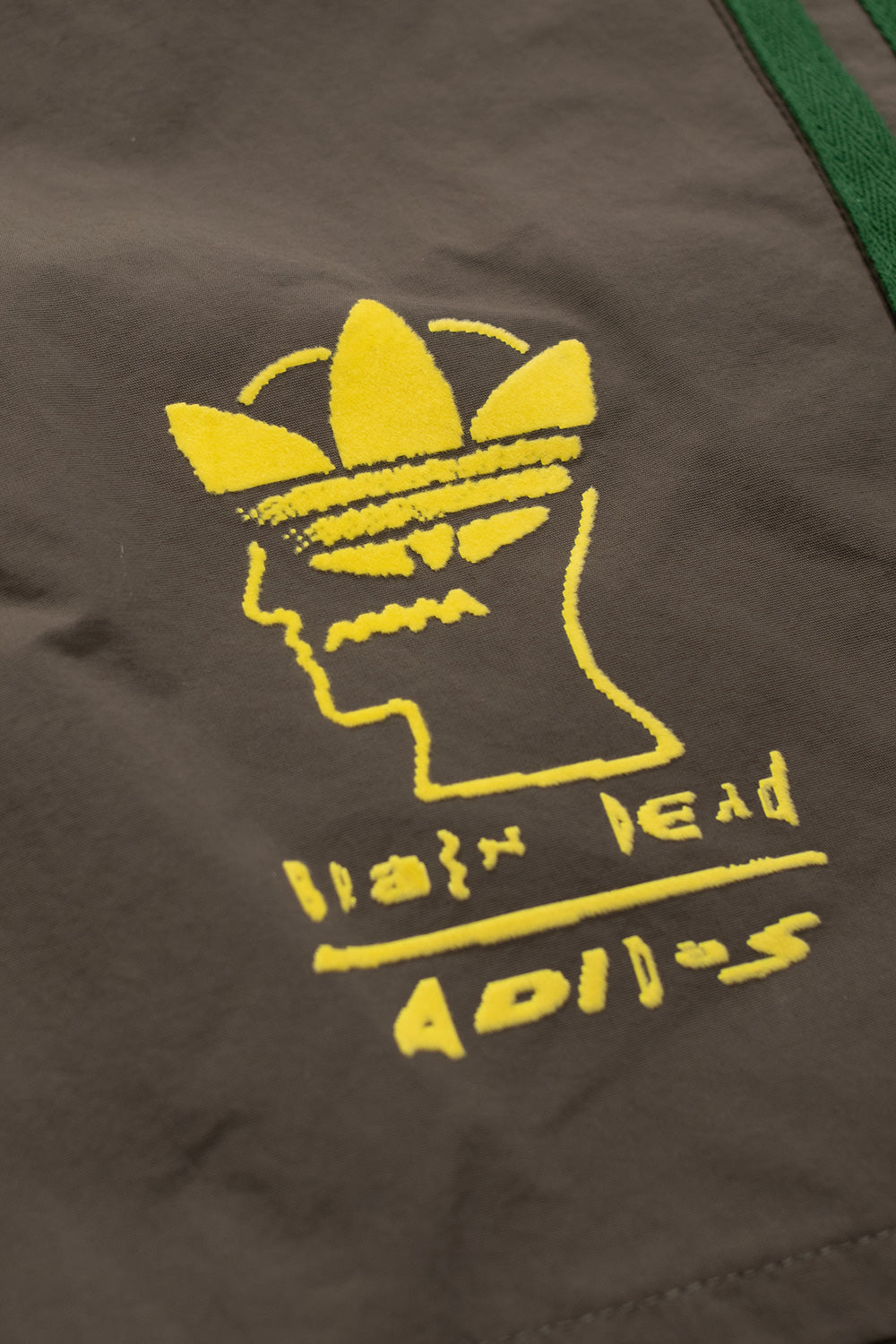 Detailaufnahme des kontraststarken Logos auf dem Bein der Adidas x Brain Dead Shorts – kreatives Crossover-Design.