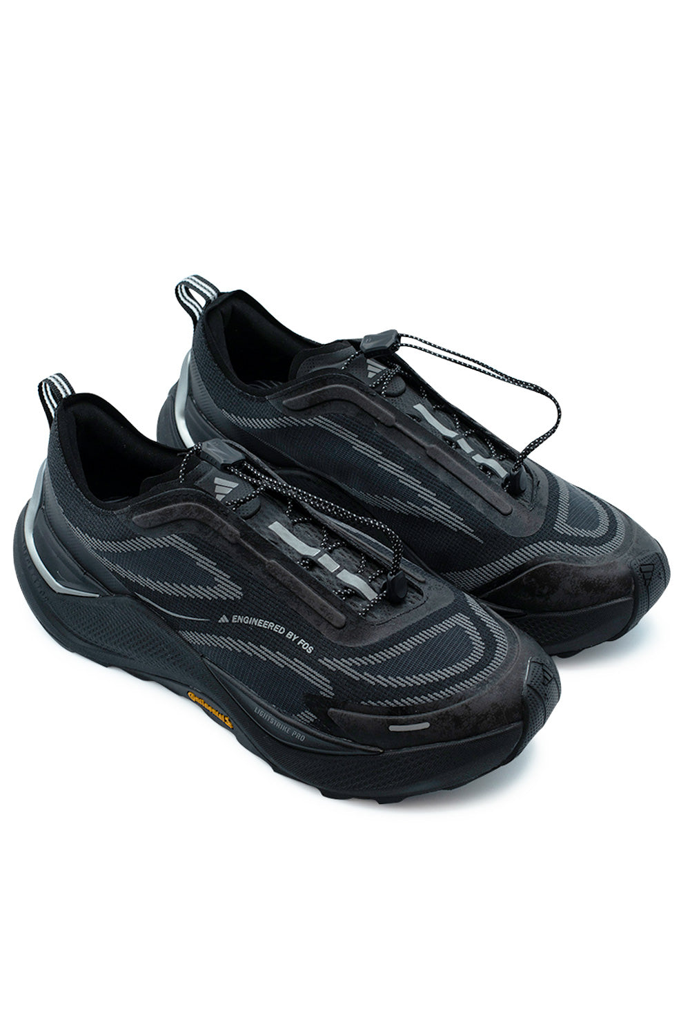Three-quarter elevated studio view of the Adidas Holo Peak outdoor sneakers in Core Black / Iron Metallic, illustrating the progressive hybrid silhouette, high-rebound trail sole unit, and streamlined speed lacing cord lock.