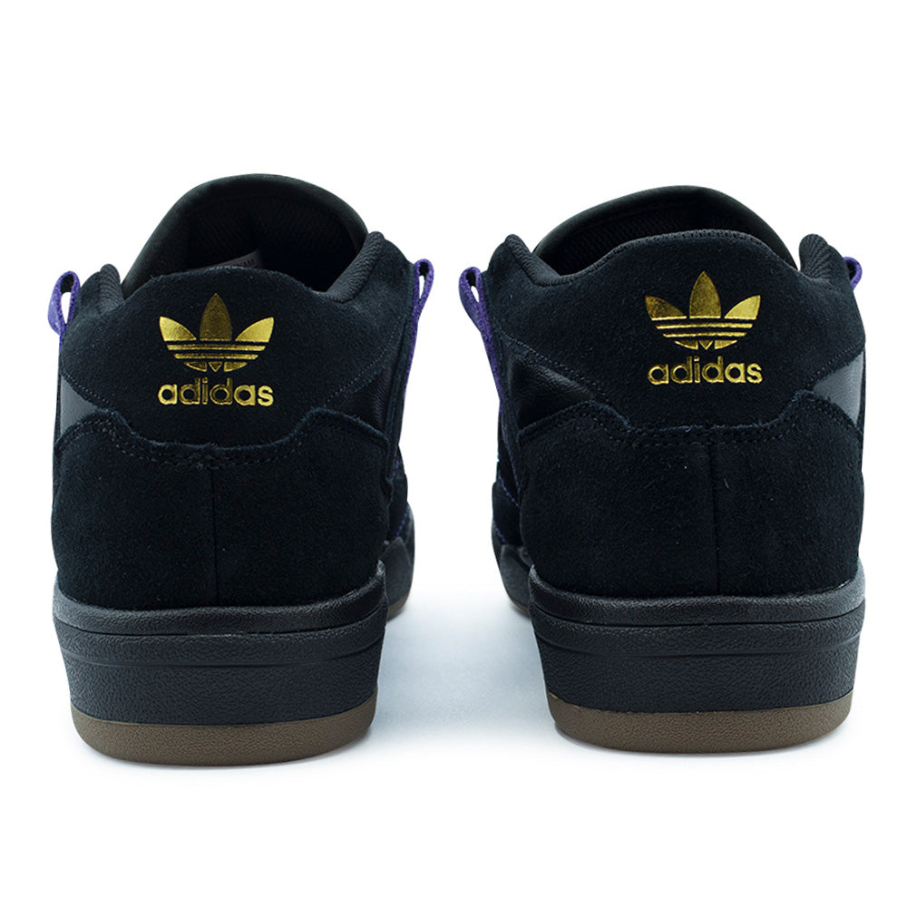 Rear studio perspective of the adidas Kader heel design, showcasing the supportive mid-cut collar padded with black mesh lining, seamless black suede heel counter panels, metallic gold foil printed adidas Trefoil logos, and textured black cupsole sidewalls.