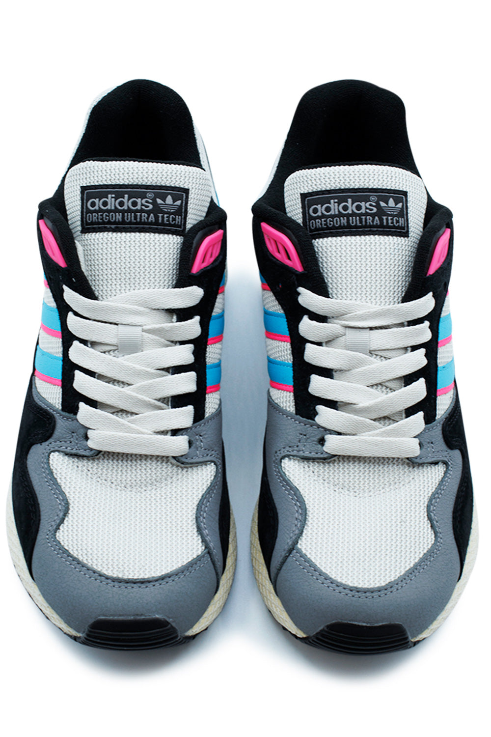 Top-down view of a pair of Adidas Oregon Ultra Tech sneakers, highlighting the white laces, grey mesh toe box, and the classic branded tongue tags.