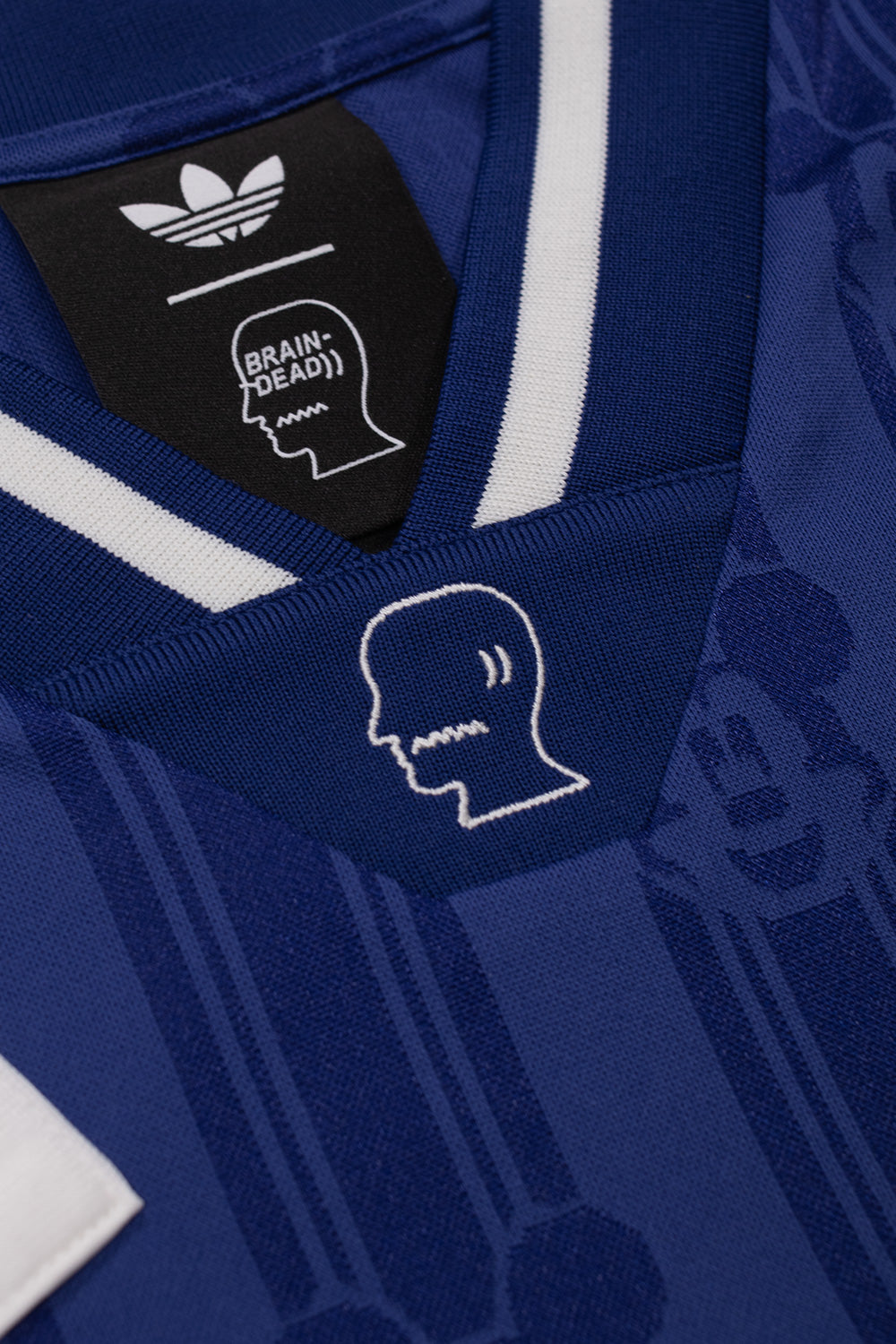 Close-up of the embroidered Brain Dead logo on the ribbed collar of the adidas x Brain Dead x Disney Football Jersey Victory Blue featuring premium neckline construction and retro football styling
