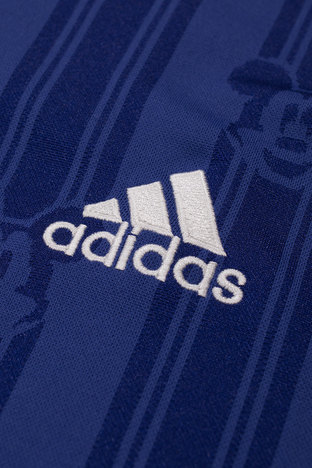 Close-up of the embroidered adidas logo on the adidas x Brain Dead x Disney Football Jersey Victory Blue showcasing premium embroidery, Mickey Mouse jacquard fabric and vintage football jersey craftsmanship