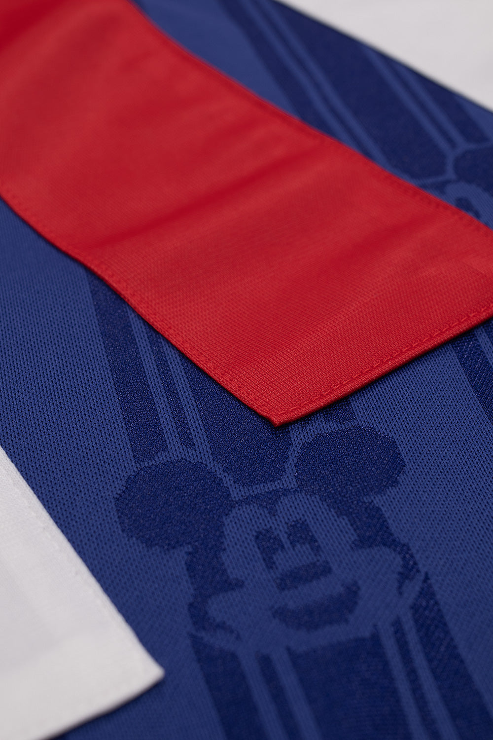 Close-up of the sewn-on red and white three stripe shoulder panels on the adidas x Brain Dead x Disney Football Jersey Victory Blue featuring premium appliqué construction and iconic adidas football heritage