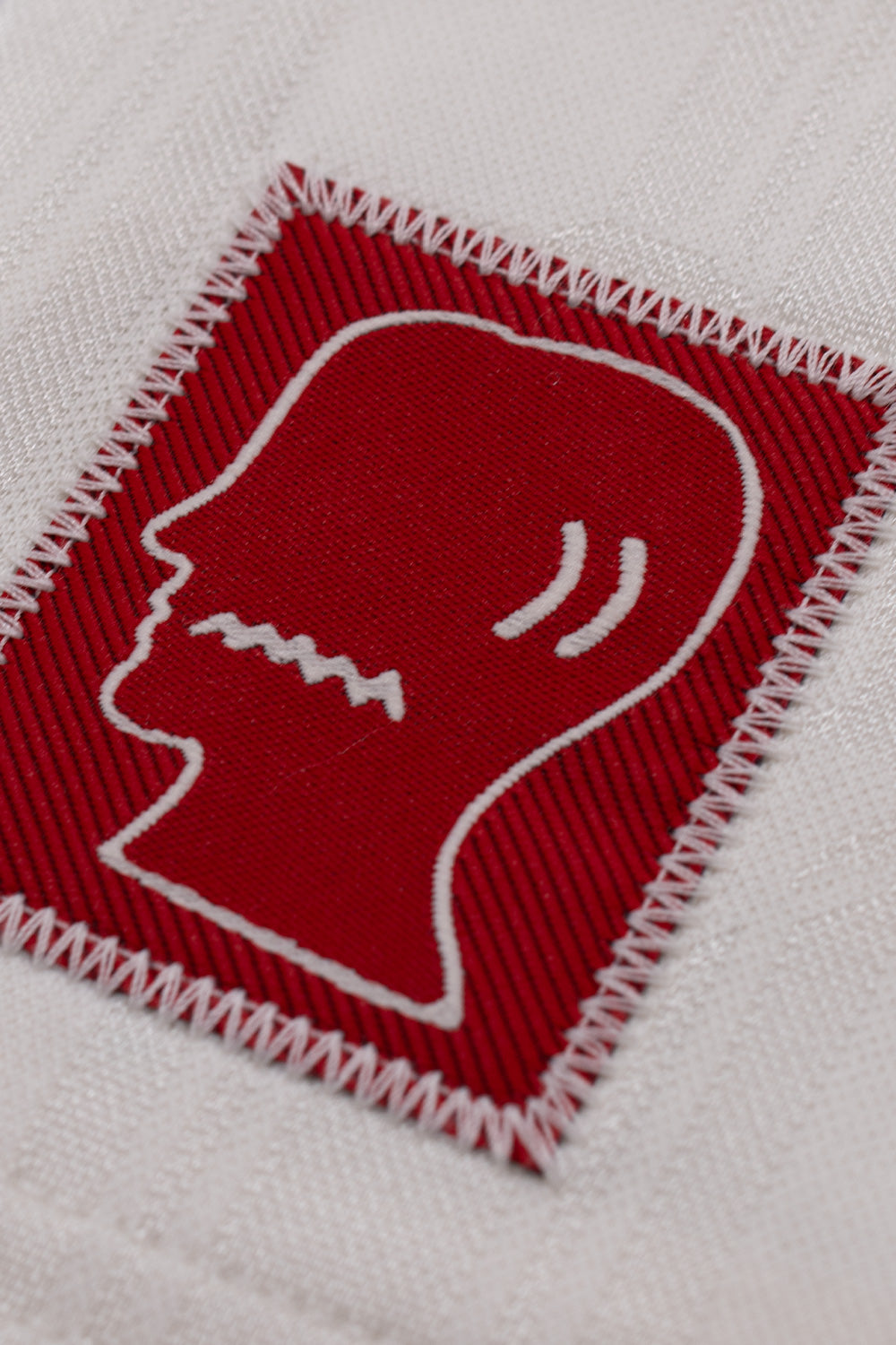 Close-up of the Brain Dead logo patch on the adidas x Brain Dead x Disney Football Short Crystal White highlighting premium stitched branding and exclusive collaboration craftsmanship