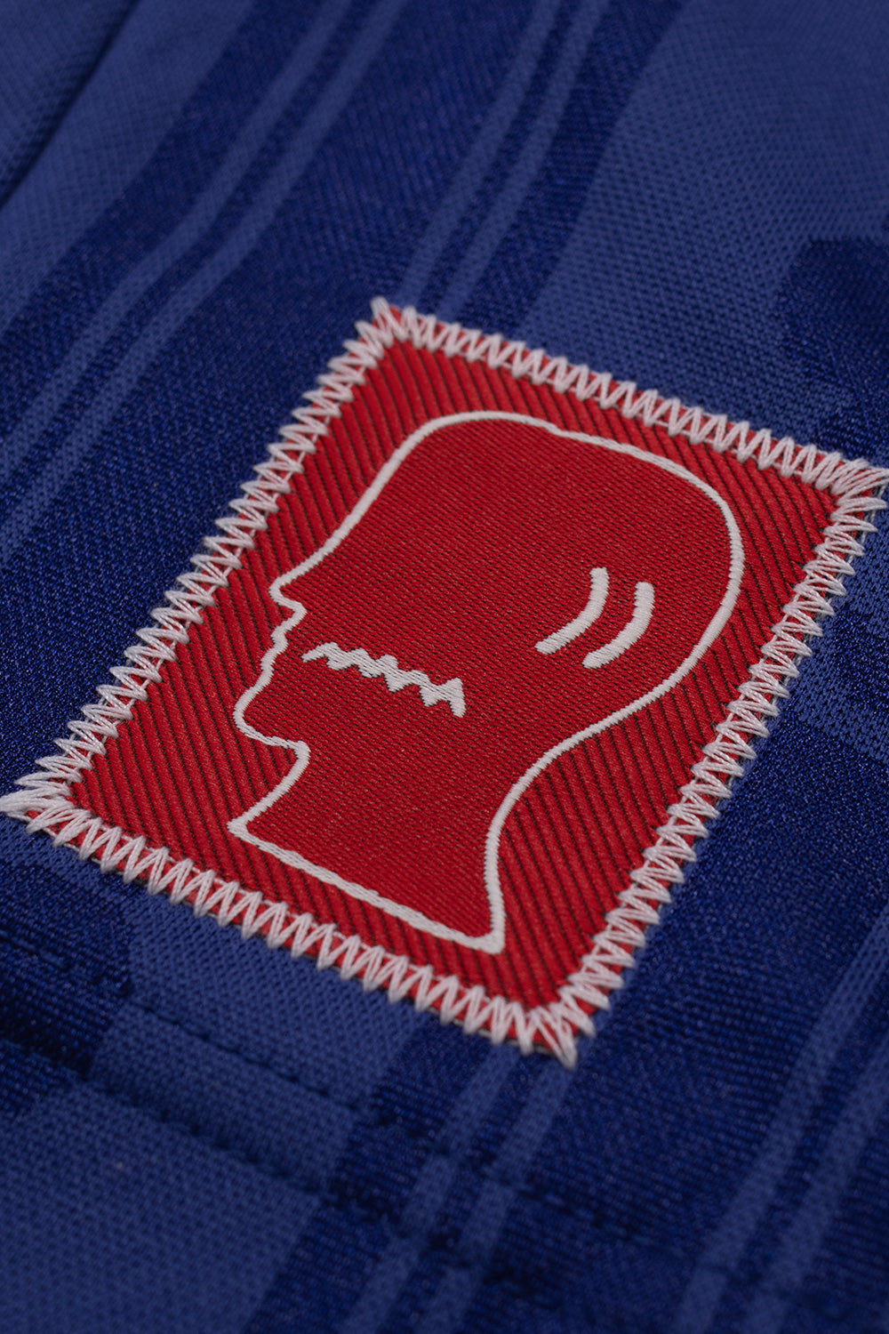 Close-up of the Brain Dead logo patch on the adidas x Brain Dead x Disney Football Short Victory Blue highlighting premium stitched branding and exclusive collaboration details