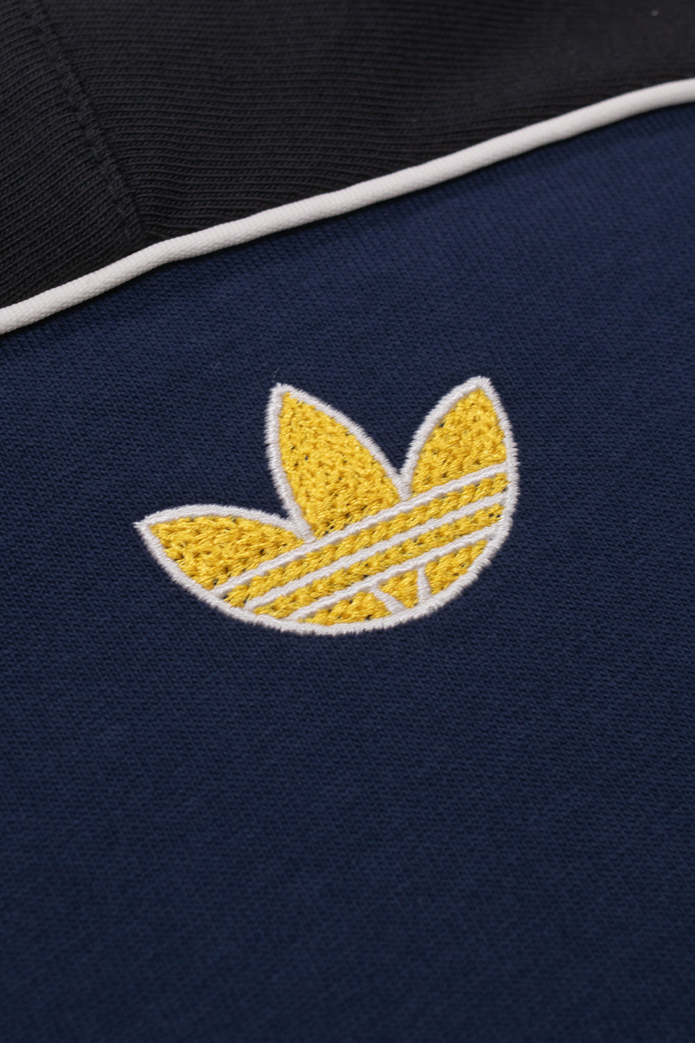 Close-up of the embroidered adidas Trefoil logo on the upper back of the Adidas x Brain Dead x Disney T-Shirt Core Navy, featuring premium embroidery, retro football styling, limited World Cup capsule collection detailing and exclusive collaborative design.