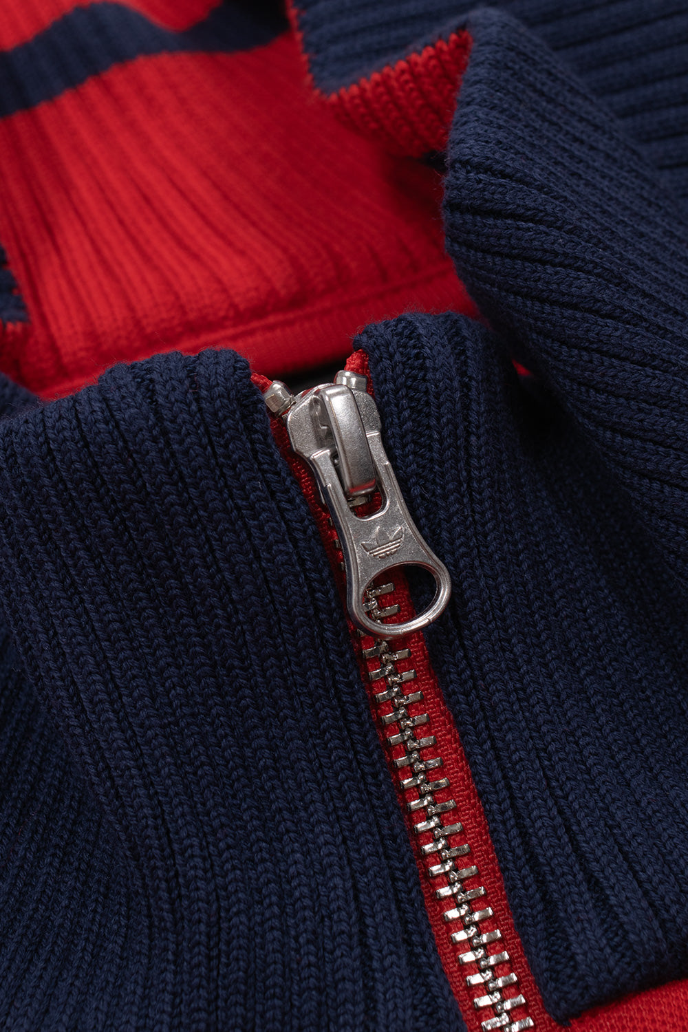 Close-up of the Adidas x Brain Dead x Disney Track Top showcasing the premium rib-knit collar, engraved adidas Originals two-way metal zipper, Better Scarlet fabric, vintage track jacket construction and high-quality craftsmanship.