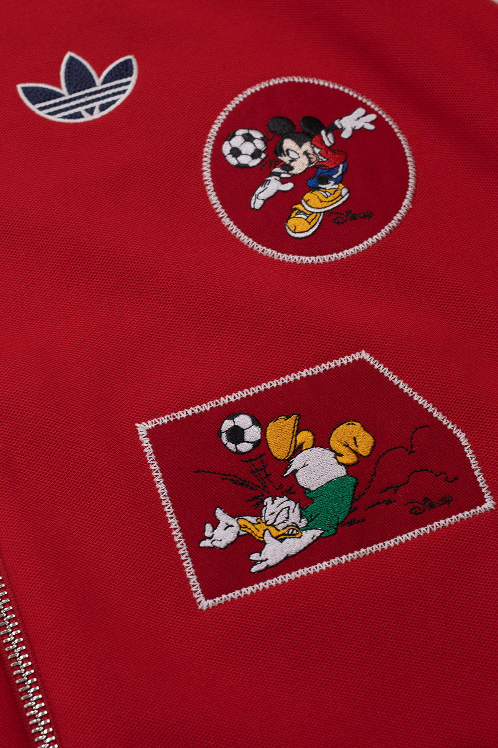 Premium embroidered Mickey Mouse and Donald Duck football patches on the Adidas Originals x Brain Dead x Disney Track Top Better Scarlet, featuring collectible Disney graphics, vintage soccer inspiration and exclusive collaborative streetwear detailing.