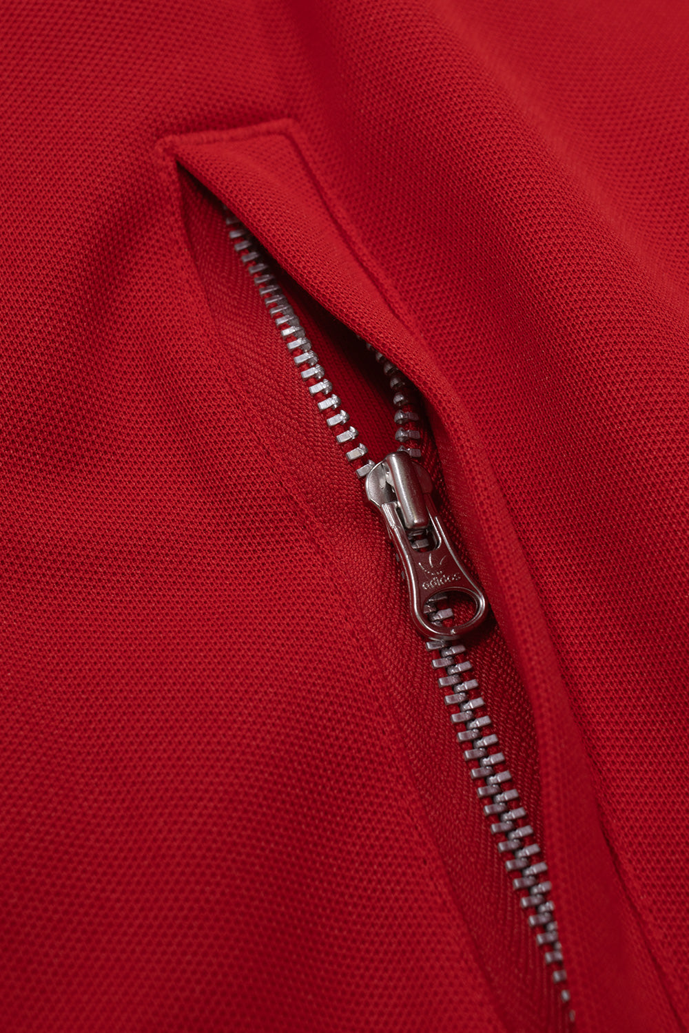 Close-up of the hidden zip side pocket on the Adidas Originals x Brain Dead x Disney Track Top Better Scarlet with premium metal zipper, durable cotton and recycled polyester blend, functional storage and authentic retro football track jacket construction.