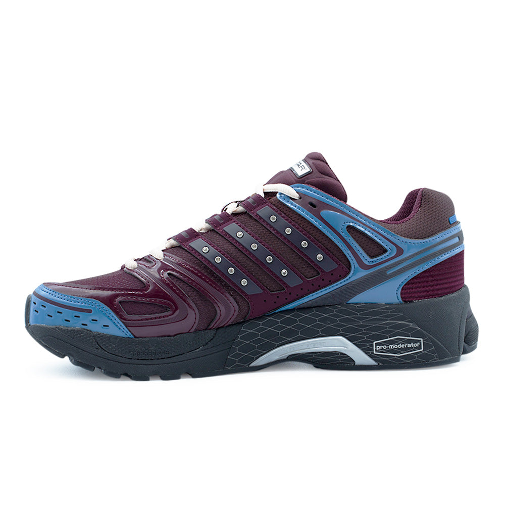 Medial inner profile view of the Adidas X Hardies Adistar Control 5 sneaker, showcasing the dusky ink blue TPU arch stabilizer, visible Pro-Moderator medial support insert on the textured black midsole, and rhinestone-detailed maroon Three Stripes.