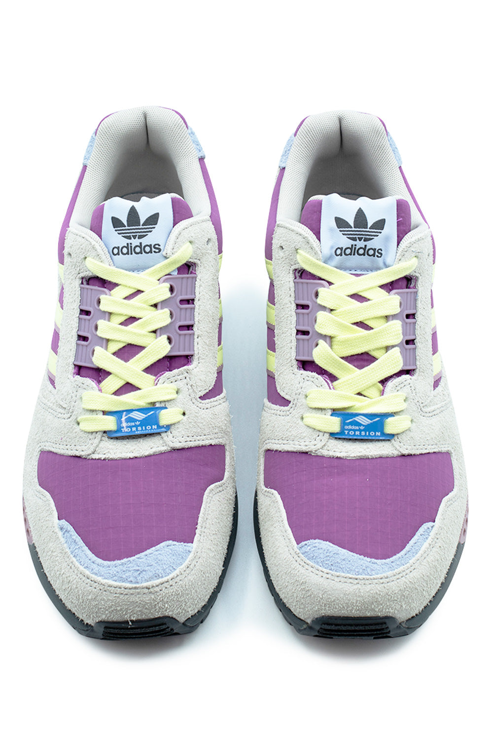 Top-down studio shot of a pair of Adidas ZX 8000 shoes, highlighting the Lucky Pink ripstop toe boxes trimmed with light blue suede tabs, hairy grey suede mudguards, pale yellow flat laces laced through TPU eyelet ghillies, bright blue Adidas Torsion lace dubraes, and white nylon tongues displaying retro Trefoil logo badges.