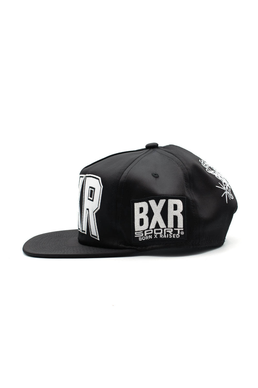 Left side view of the black shiny polyester Born X Raised cap, showcasing the sewn-on rectangular BXR SPORT BORN X RAISED patch.