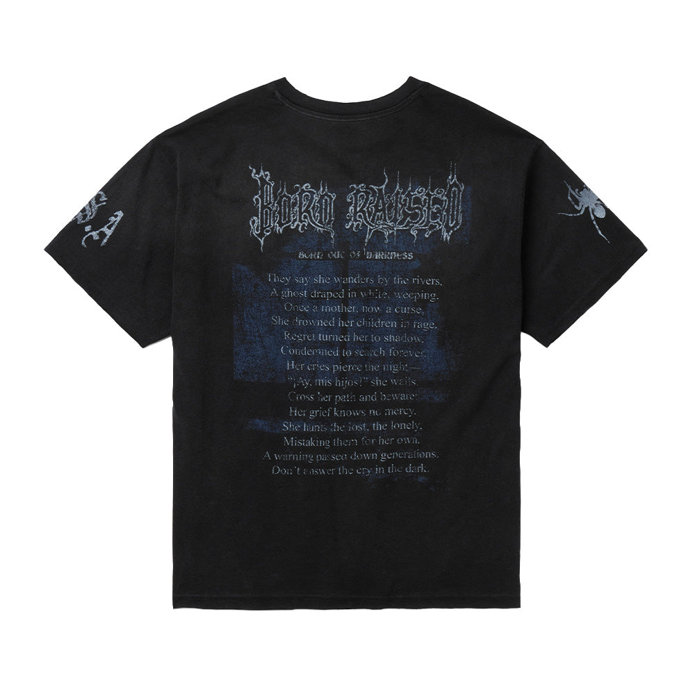 Back flat lay studio perspective of the vintage black Born X Raised Llorona T-Shirt, highlighting the full-length folklore back print featuring arched "BORN RAISED" metal lettering, the subtitle "BORN OUT OF DARKNESS", a fourteen-line English poem narrating the tragic myth of La Llorona over faded cross graphics, and sleeve art depicting a realistic spider and stylized lettering.