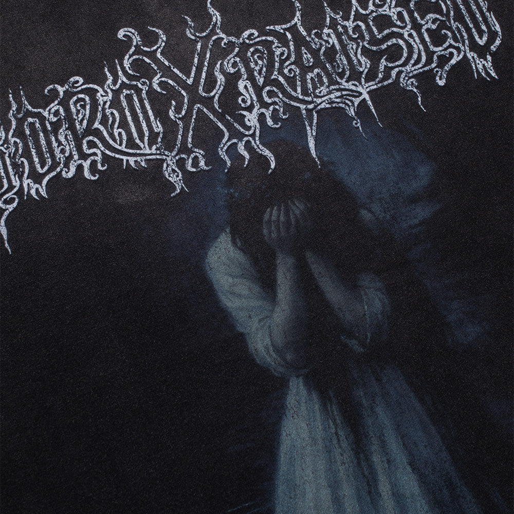 Detailed macro perspective of the front graphic on the Born X Raised Llorona T-Shirt, capturing the intricate hand-drawn texture of the thorny, dripping black-metal "BORN X RAISED" band font and the dark, atmospheric portrait of the weeping woman in a white gown covering her face in grief.