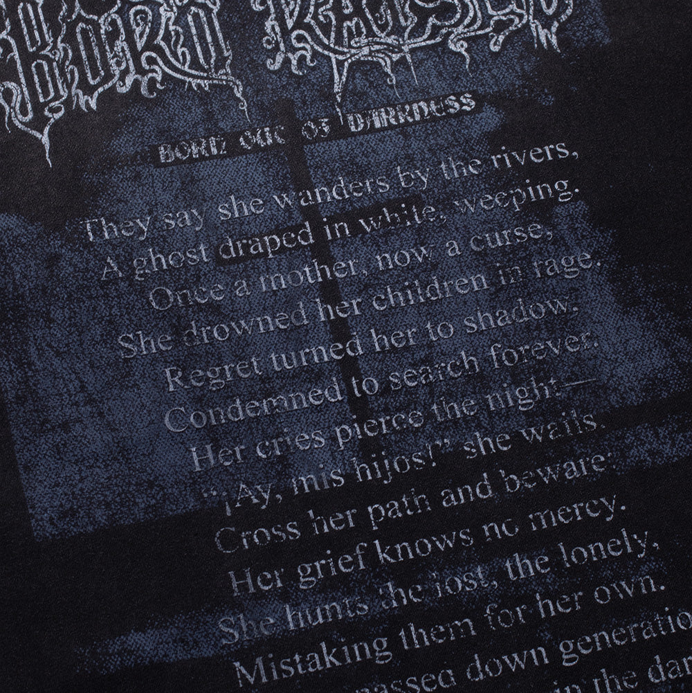 Macro studio view of the back typography on the Born X Raised Llorona T-Shirt, detailing the cracked, aged white ink printing the mythological poem beginning with "They say she wanders by the rivers" and warning "Don't answer the cry in the dark" across the textured vintage black cotton.