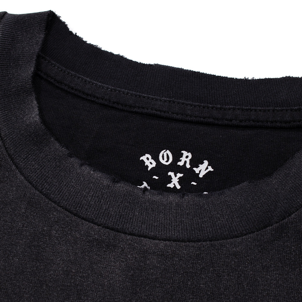 Extreme macro close-up of the neckline on the Born X Raised Llorona T-Shirt, displaying the custom factory-distressed, frayed raw-edge rib knit collar and the interior printed white neck label featuring arched "BORN X RAISED" Gothic branding.