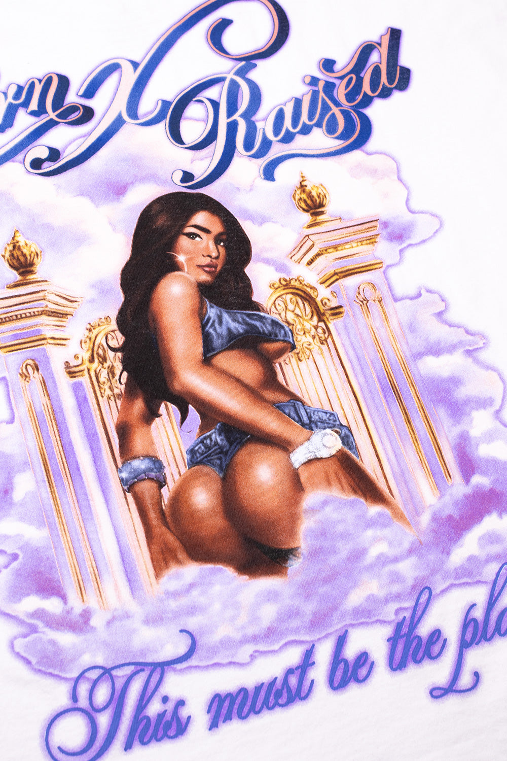 Close-up detail of the detailed back graphic print showing a woman in front of golden gates and purple clouds with the text This must be the place.