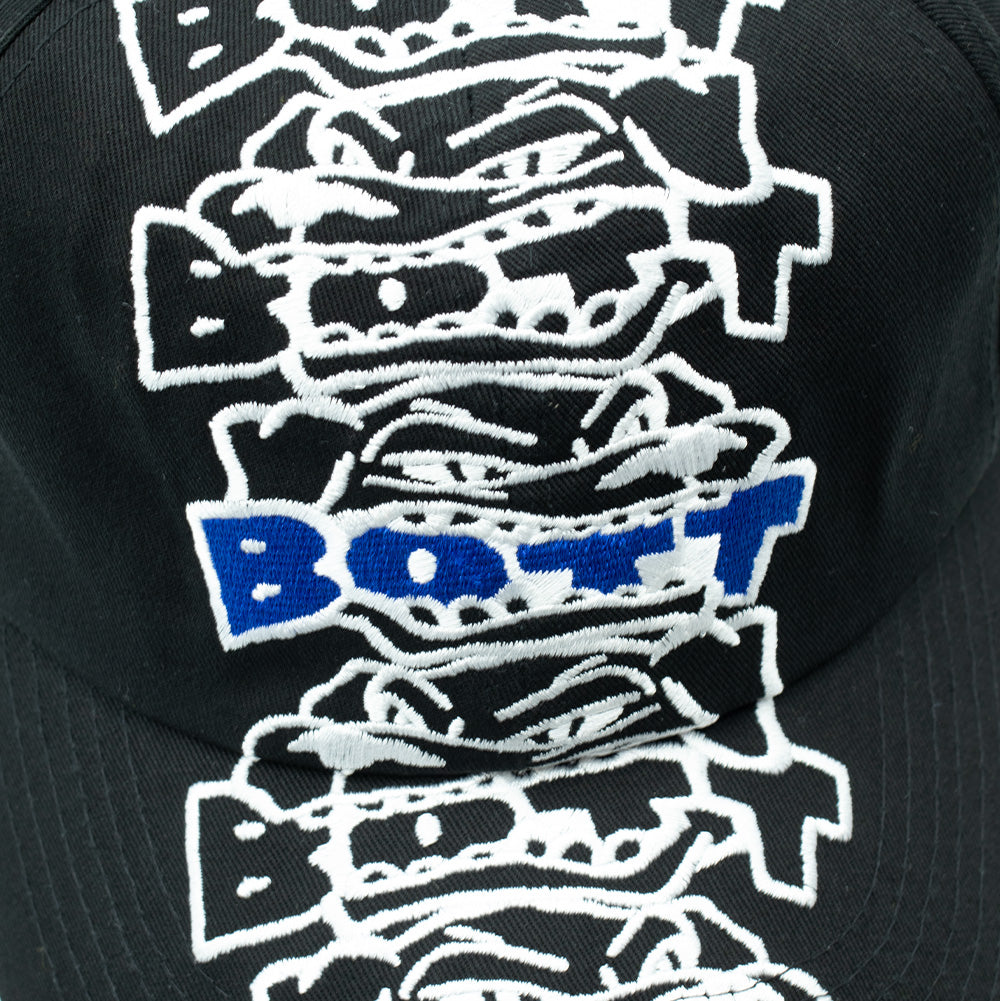 Detailed macro studio close-up of the crown embroidery on the BoTT Bottweiler 6 Panel Cap, capturing the dense white satin-stitch outlines of the aggressive cartoon dog faces biting down on block typography, accented by electric royal blue thread filling the central "BoTT" logo against black cotton fabric.