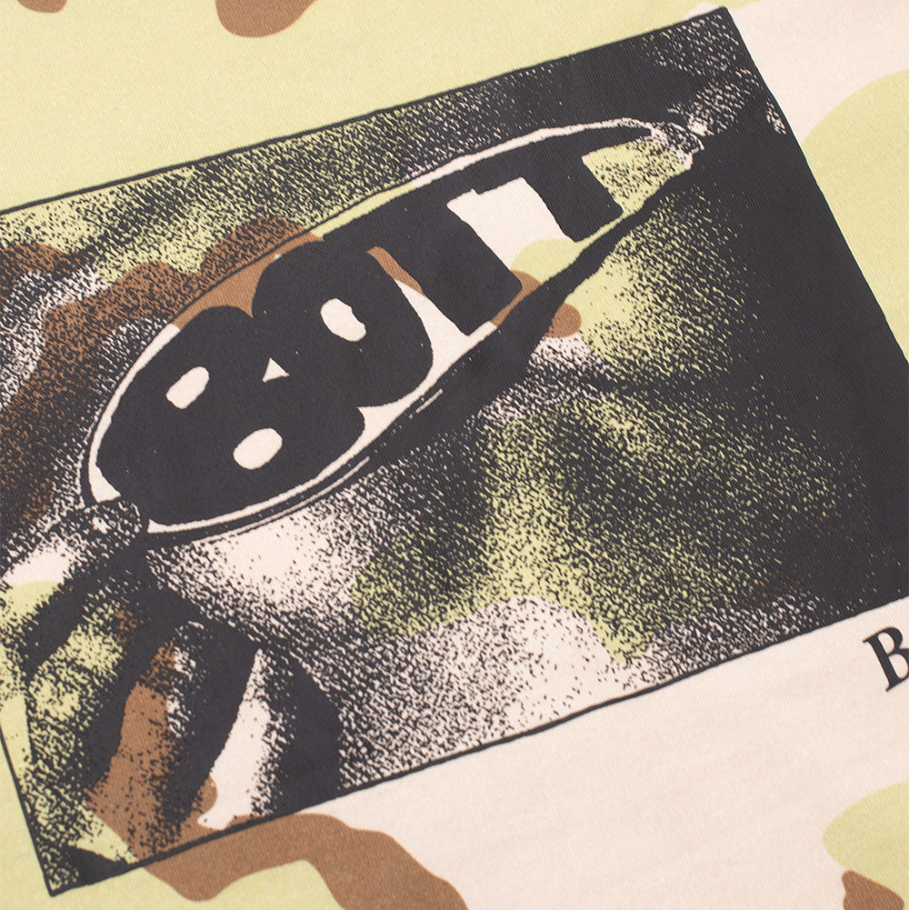 Detailed macro perspective of the chest graphic on the BoTT Lust Camo T-Shirt, showing the grainy black-and-white halftone photographic print of retro oval sunglasses stamped with bold black "BOTT" bubble lettering, set against the smooth desert camo cotton fabric.