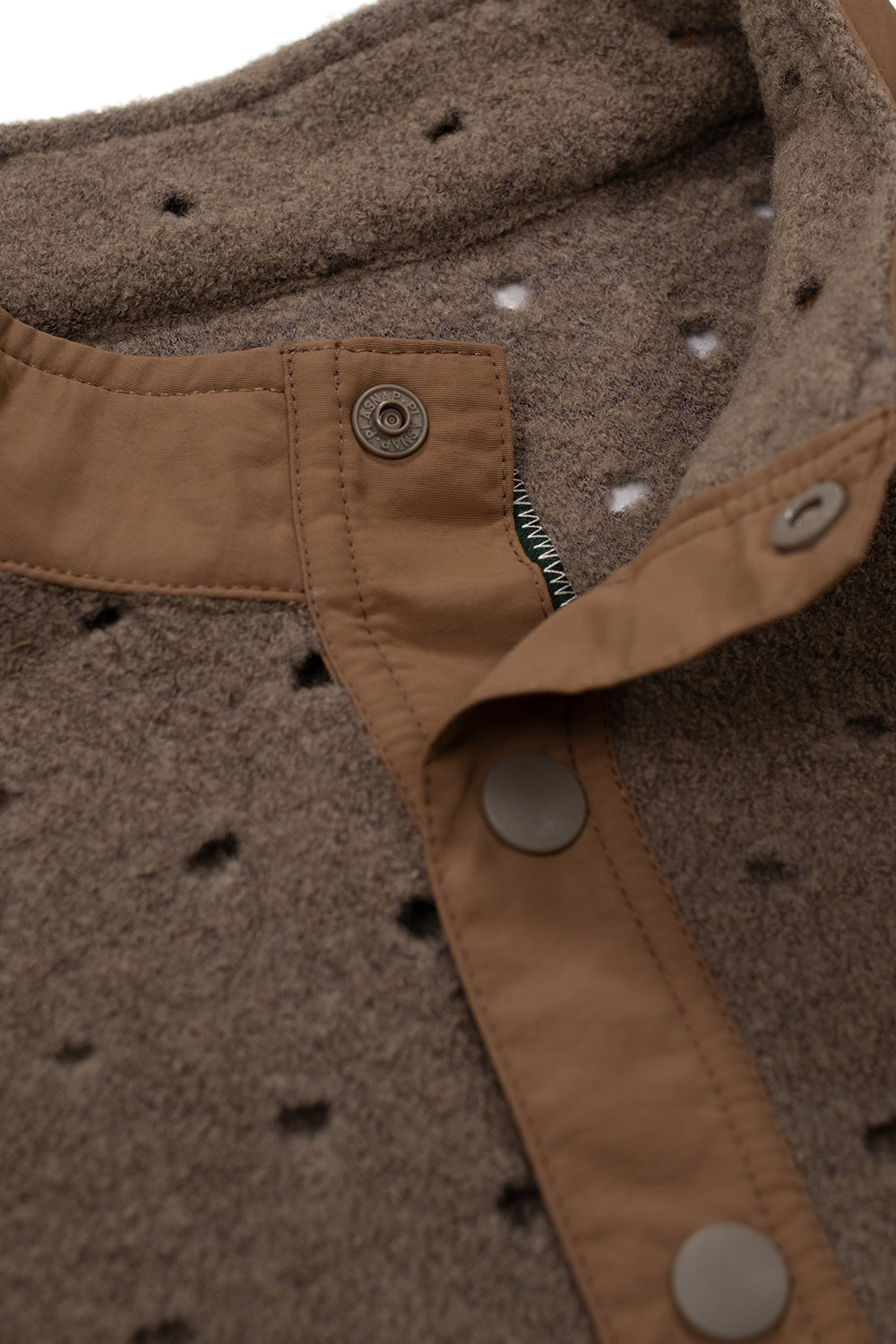 Close-up of the Brain Dead Hole Mock Neck Pullover Brown mock neck with snap button placket, premium wool blend construction, contrast nylon trim and laser-cut perforations