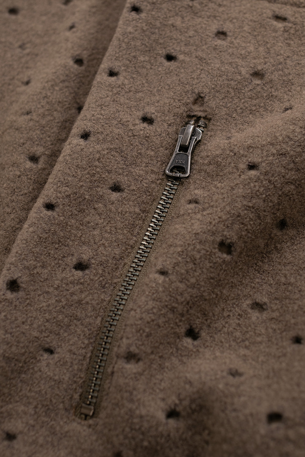 Close-up of the Brain Dead Hole Mock Neck Pullover Brown YKK zip side pocket highlighting laser-cut wool fabric, functional storage and premium craftsmanship