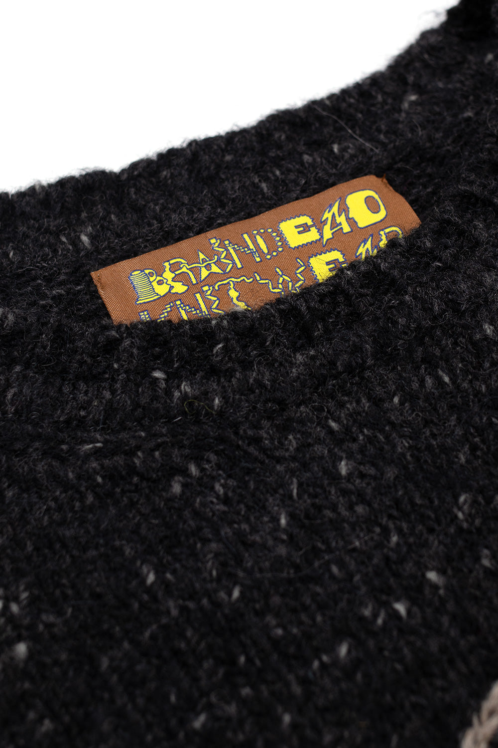 Close-up of Brain Dead Logohead Alpaca Crewneck Sweater Charcoal highlighting textured alpaca merino wool knit fabric and woven Brain Dead Los Angeles brand label inside the crewneck collar