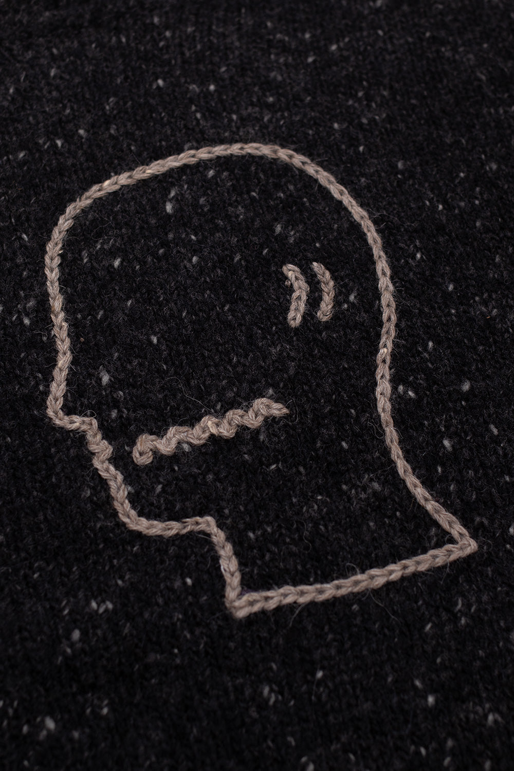 Macro detail of Brain Dead Logohead Alpaca Crewneck Sweater Charcoal showing embroidered Brain Dead head logo artwork stitched onto charcoal alpaca merino knit sweater from the LA underground streetwear label
