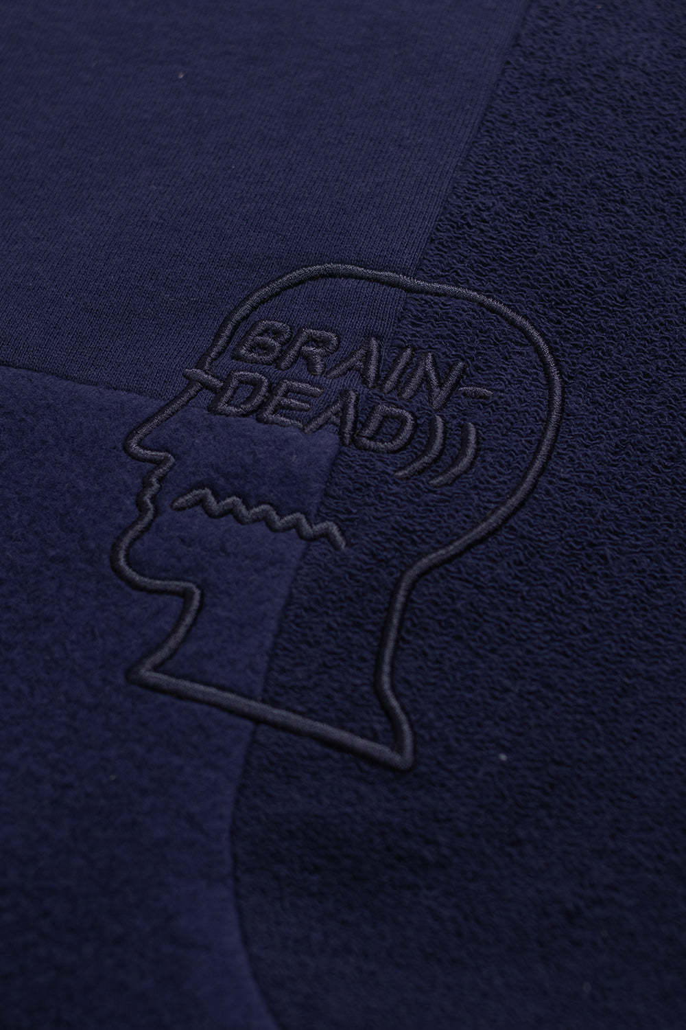 Detailaufnahme der Brustpartie des Brain Dead Longsleeves mit hochwertigem Material-Mix und Label-Logo