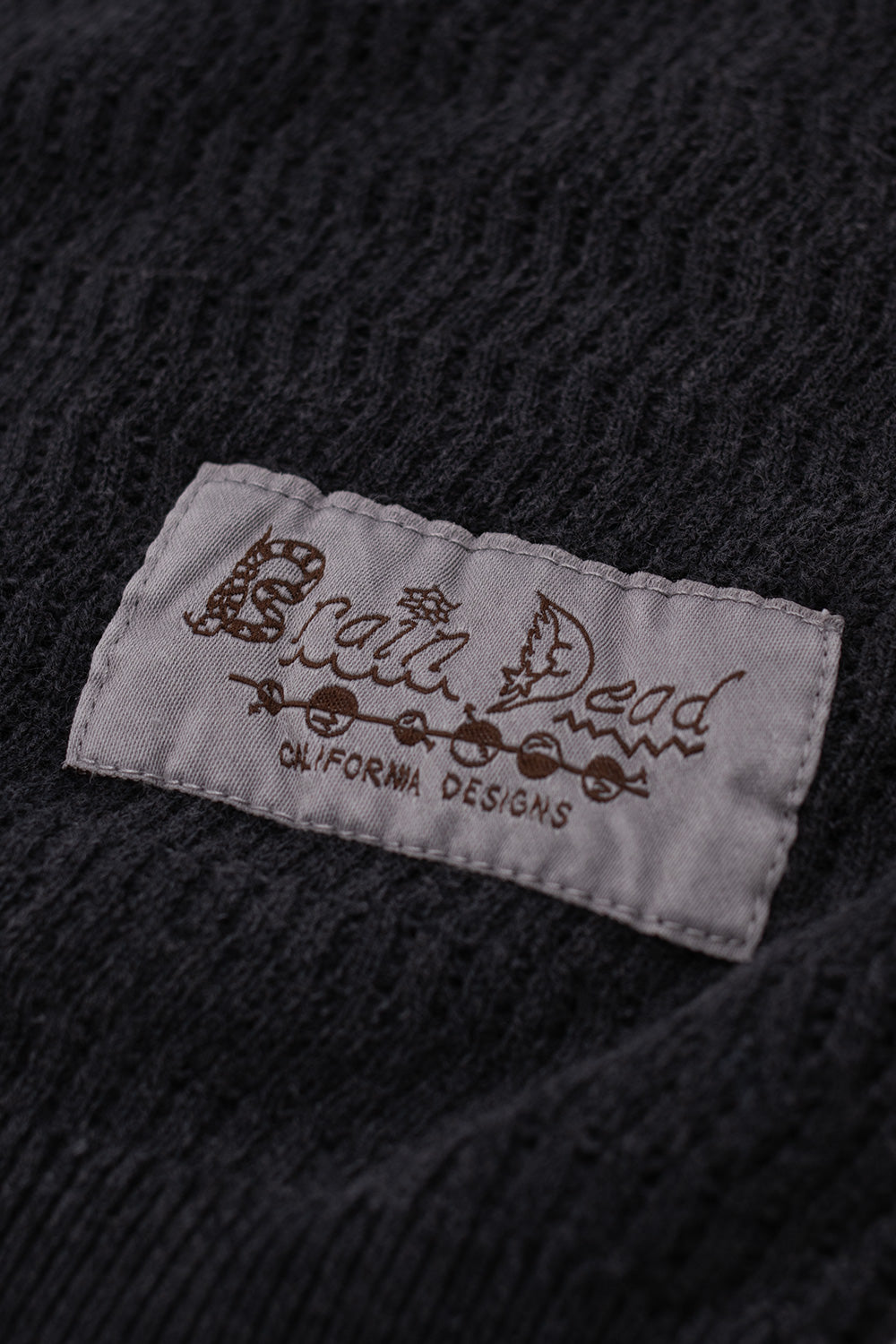 Brain Dead Pigment Dye Long Sleeve Polo Sweater Ink logo patch – side logo label on knitted polo sweater made in Peru