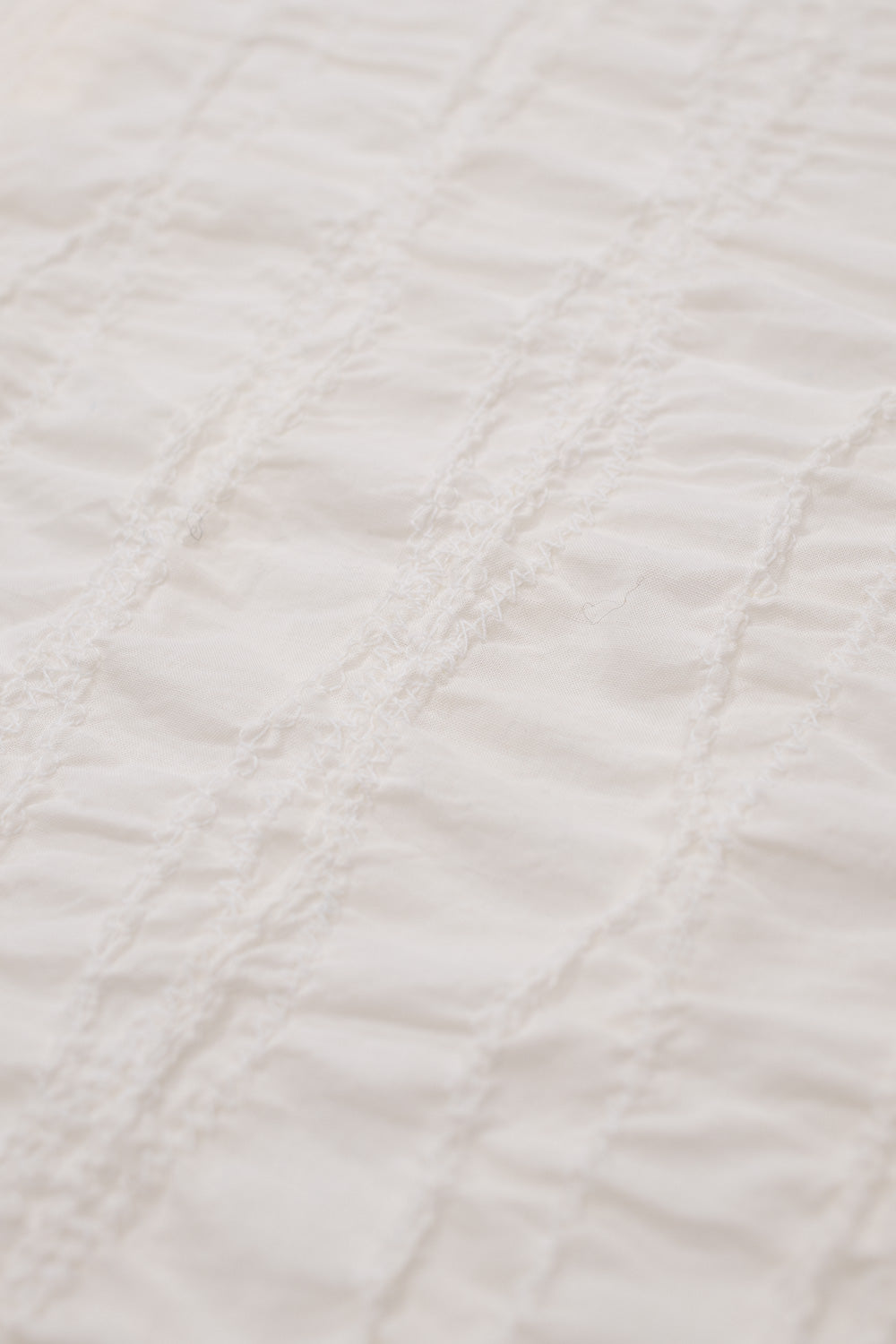 Macro detail of Brain Dead Twisted Piping Shirt Natural displaying intricate fully embroidered cotton fabric texture and lightweight breathable weave on contemporary Brain Dead streetwear button shirt