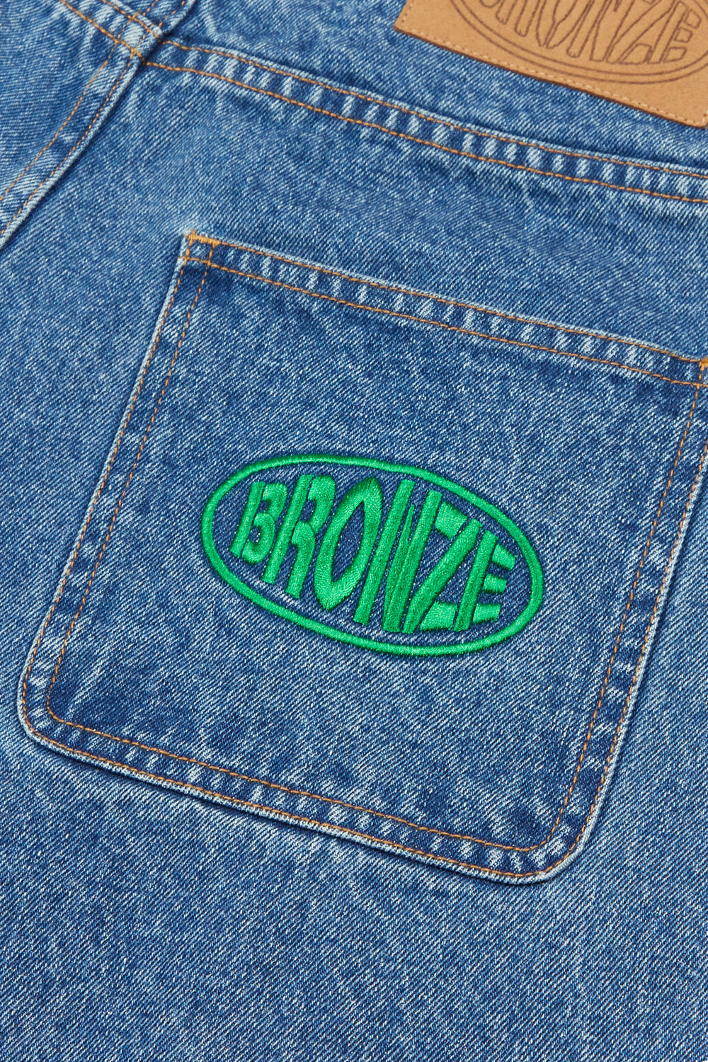 "Detailaufnahme der blauen Bronze 56K Denim Jorts – markantes Logo-Patch und strapazierfähiges Material"