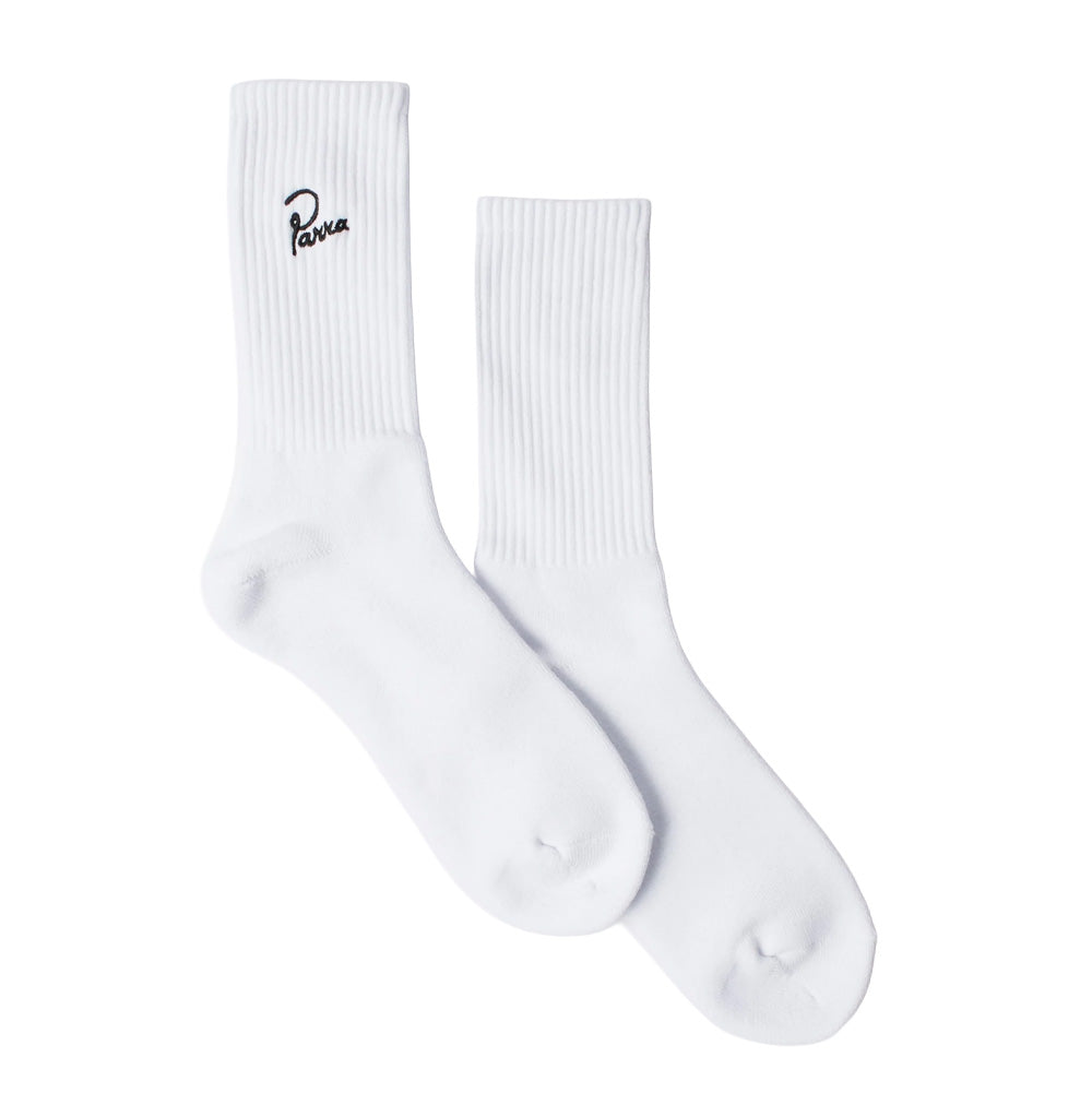 Studio flat lay display of a pair of By Parra Signature Crew Socks in optic white, showcasing the mid-calf athletic ribbed leg with elasticated arch support and smooth reinforced heel and toe construction, expertly crafted in Japan from a premium cotton-blend knit and finished with black cursive "Parra" signature logo embroidery on the outer upper ribbed cuff.