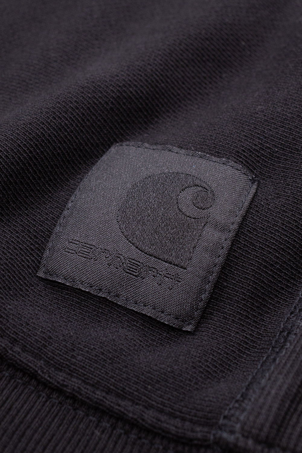 "Detailaufnahme des Carhartt WIP Dawson Sweatshirts in Black – hochwertiges gesticktes Logo auf der Brust für dezente Markenakzente"