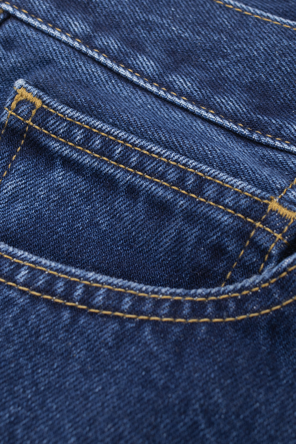 Extreme close-up shot of the curved front right coin pocket on the Carhartt WIP Payson Pant in Blue Stone Washed, detailing the textured twill grain of the stone-washed denim fabric, reinforced bar-tack stitching, and double contrast gold stitch lines.