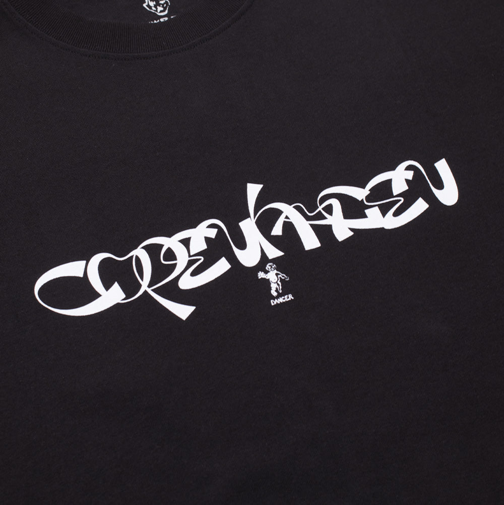 Angled studio close-up of the front graphic print on the black Dancer Copenhagen T-Shirt, displaying the crisp white screen-printed abstract cursive lettering with the small printed angel mascot and "DANCER" block text positioned neatly underneath on pure black cotton fabric.