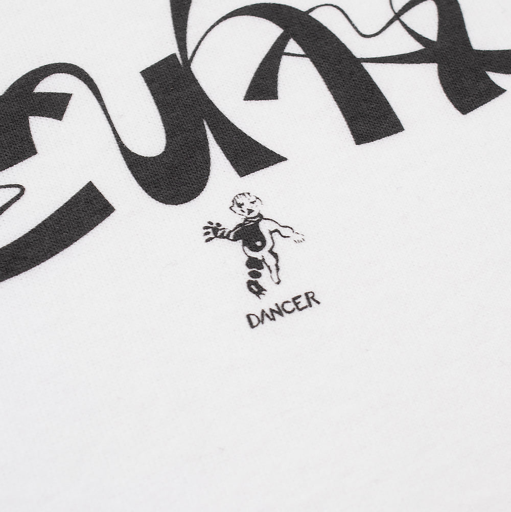 Detailed macro studio shot of the logo on the Dancer Copenhagen T-Shirt in white, highlighting the clean black line-work of the dancing cherub figurine and bold "DANCER" lettering positioned below the curved swashes of the calligraphic script print on smooth organic cotton weave.