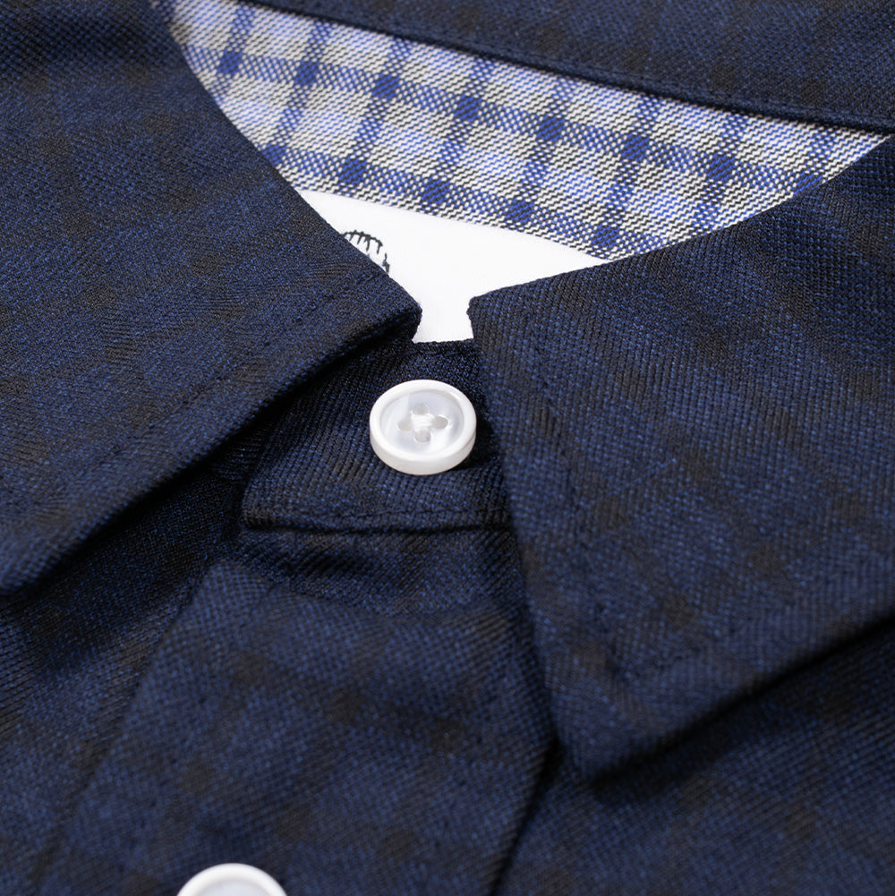 Macro studio close-up of the collar and upper neckline on the Dancer Split Checked Shirt, showcasing the dark navy check point collar, four-hole white pearlized button closure, and the inner white brand label nestled within the light blue check lining.