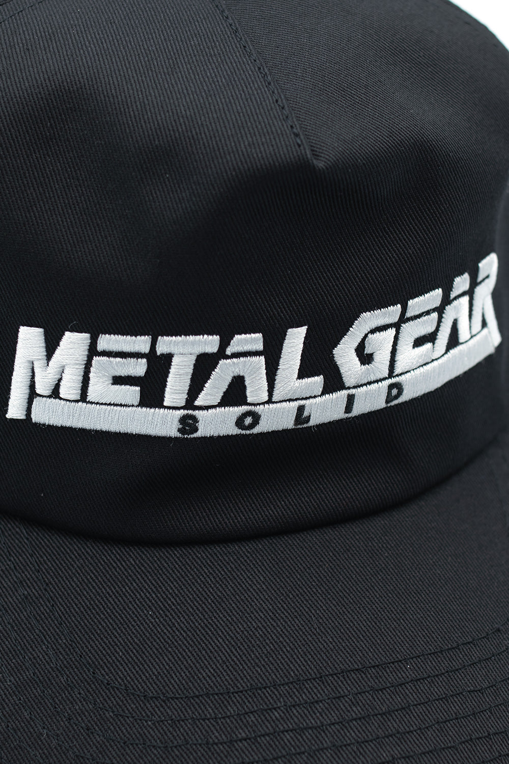 Close-up of embroidered Metal Gear Solid logo on black HUF snapback cap from Legacy Collection, inspired by Yoji Shinkawa artwork