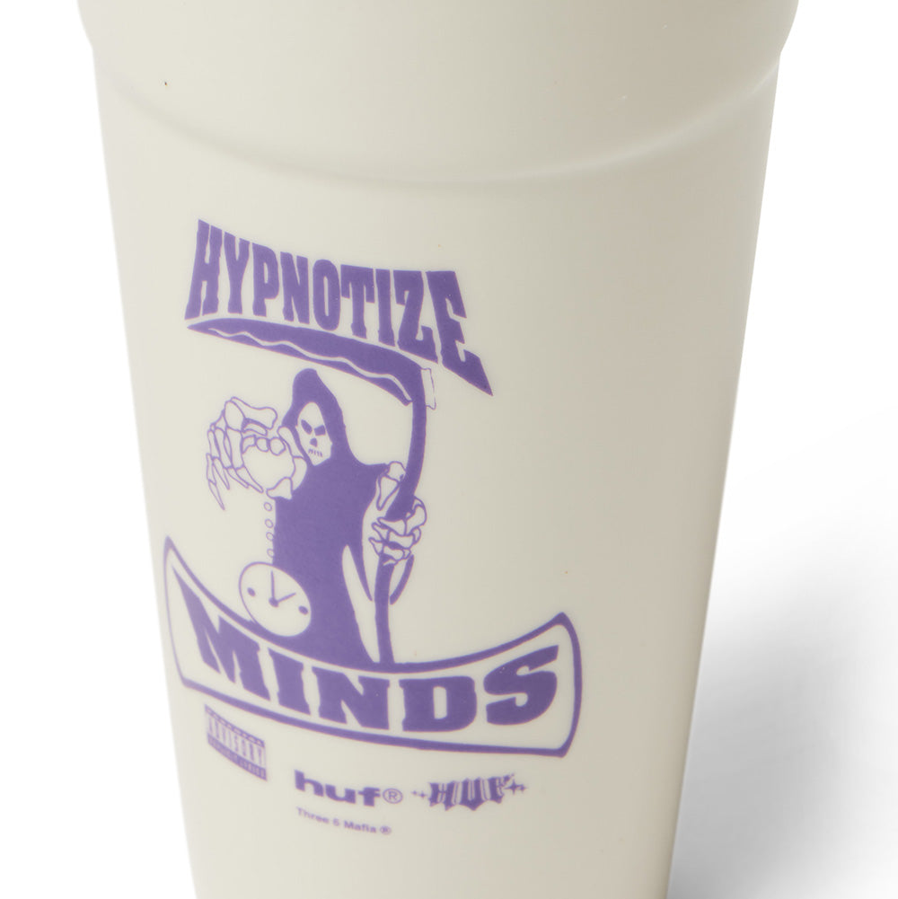 Macro close-up detail of the front graphic on the Huf X Three 6 Mafia Ceramic Double Cup, showing the crisp purple glazed ceramic decal featuring the hooded grim reaper holding an hourglass, "HYPNOTIZE MINDS" arched banners, "huf®", and miniature "Three 6 Mafia ®" copyright text.