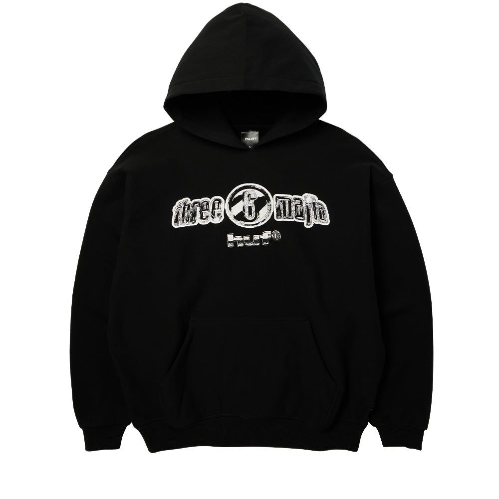 Front flat lay view of the black Huf X Three 6 Mafia Heavyweight Hoodie, showcasing a premium heavy cotton fleece pullover silhouette with a spacious double-layer hood, roomy front kangaroo pouch pocket, wide ribbed cuffs and waistband, and a contrasting white screen-printed graphic across the center chest displaying the Y2K chrome Three 6 Mafia circular emblem above the clean "huf®" logo.