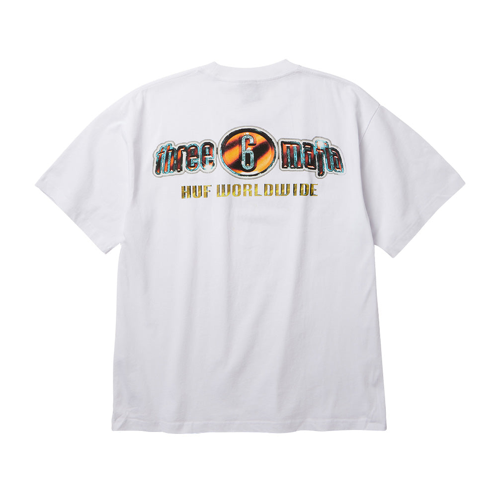 Back flat lay view of the white Huf X Three 6 Mafia Smoke Clears T-Shirt, showcasing an oversized Y2K hip hop back print with metallic chrome and orange-tinted "three 6 mafia" bubble lettering featuring a stylized circular emblem around the numeral 6, arched above golden gradient "HUF WORLDWIDE" block text.