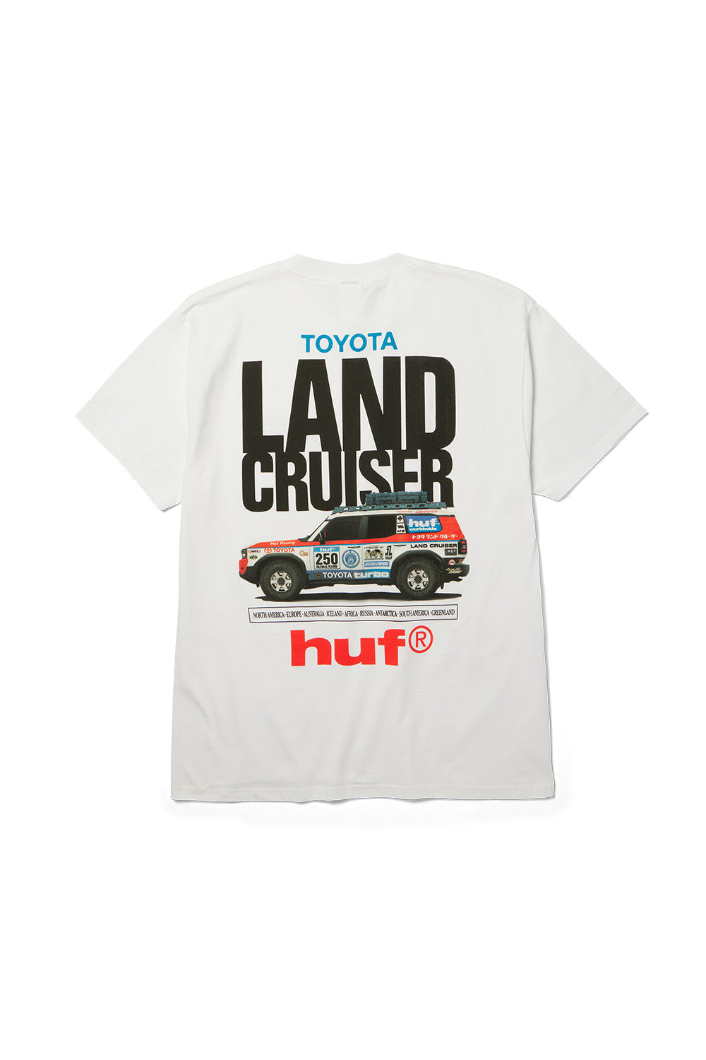 Back flat lay view of the white Huf X Toyota Land Cruiser Rally SS T-Shirt made from 200g cotton jersey, showcasing a vibrant motorsport back print with large black condensed "LAND CRUISER" typography, blue "TOYOTA" lettering, an illustrated off-road rally vehicle loaded with a rooftop expedition rack and sponsor decals, a global continent list, and a bold red lowercase "huf®" logo.