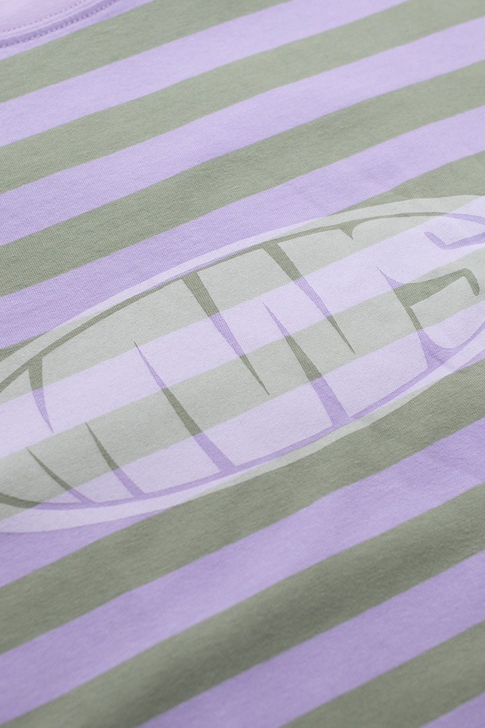 Close-up of Metalwood Studio Bulge Logo graphic on pink and green striped long sleeve tee – detailed chest print on soft cotton-spandex blend fabric.