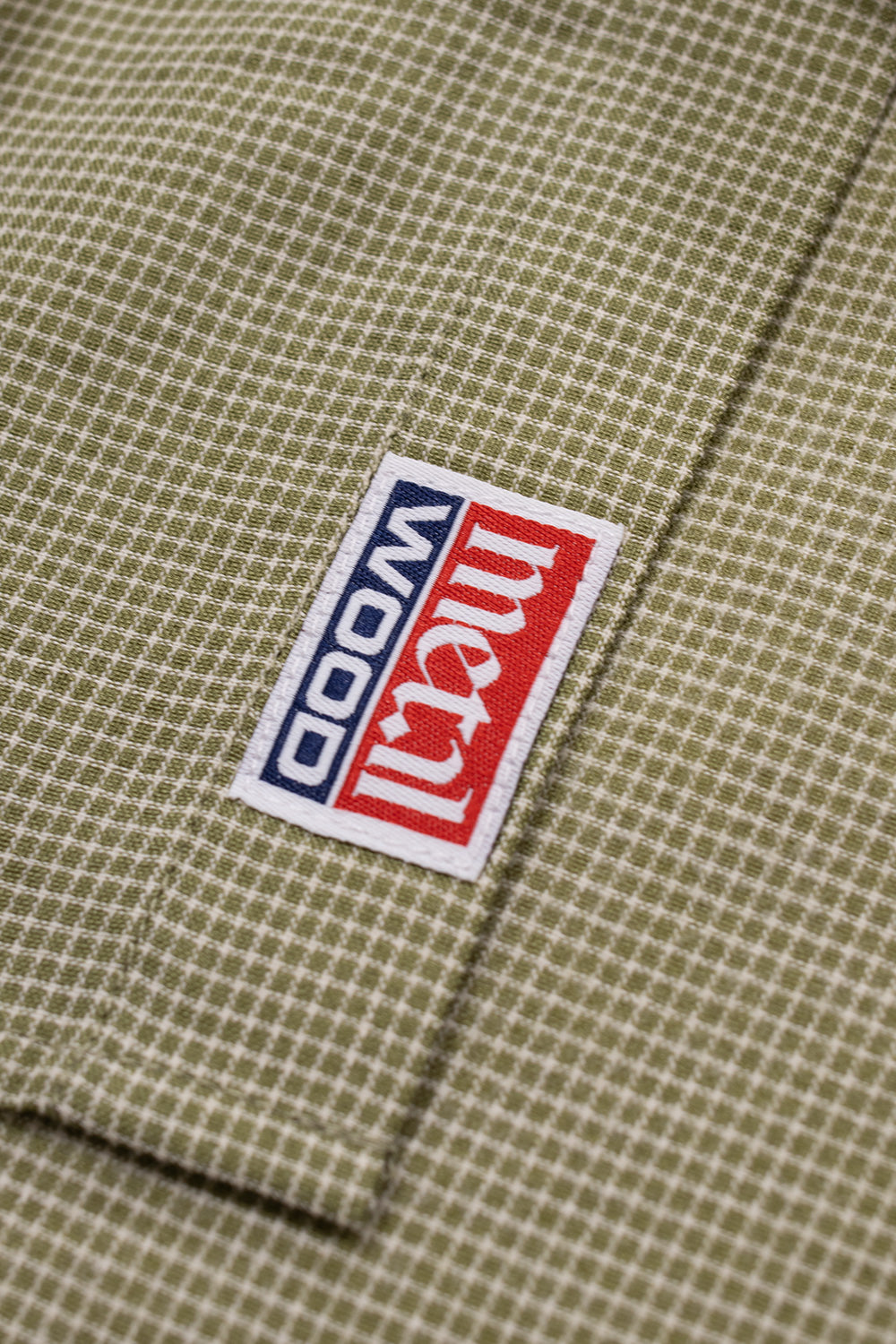 Metalwood Studio logo tag detail on an oversized green button up shirt inspired by vintage sportswear, golf apparel and contemporary streetwear culture