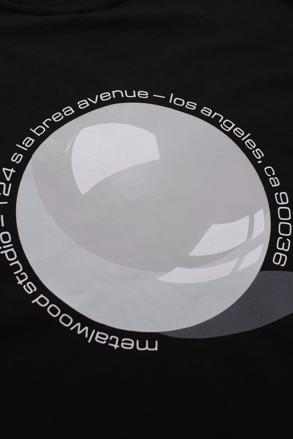 Close-up of the printed back graphic on the Metalwood Studio Pool T-Shirt Black, featuring glossy sphere artwork and circular Los Angeles text on premium heavy cotton.
