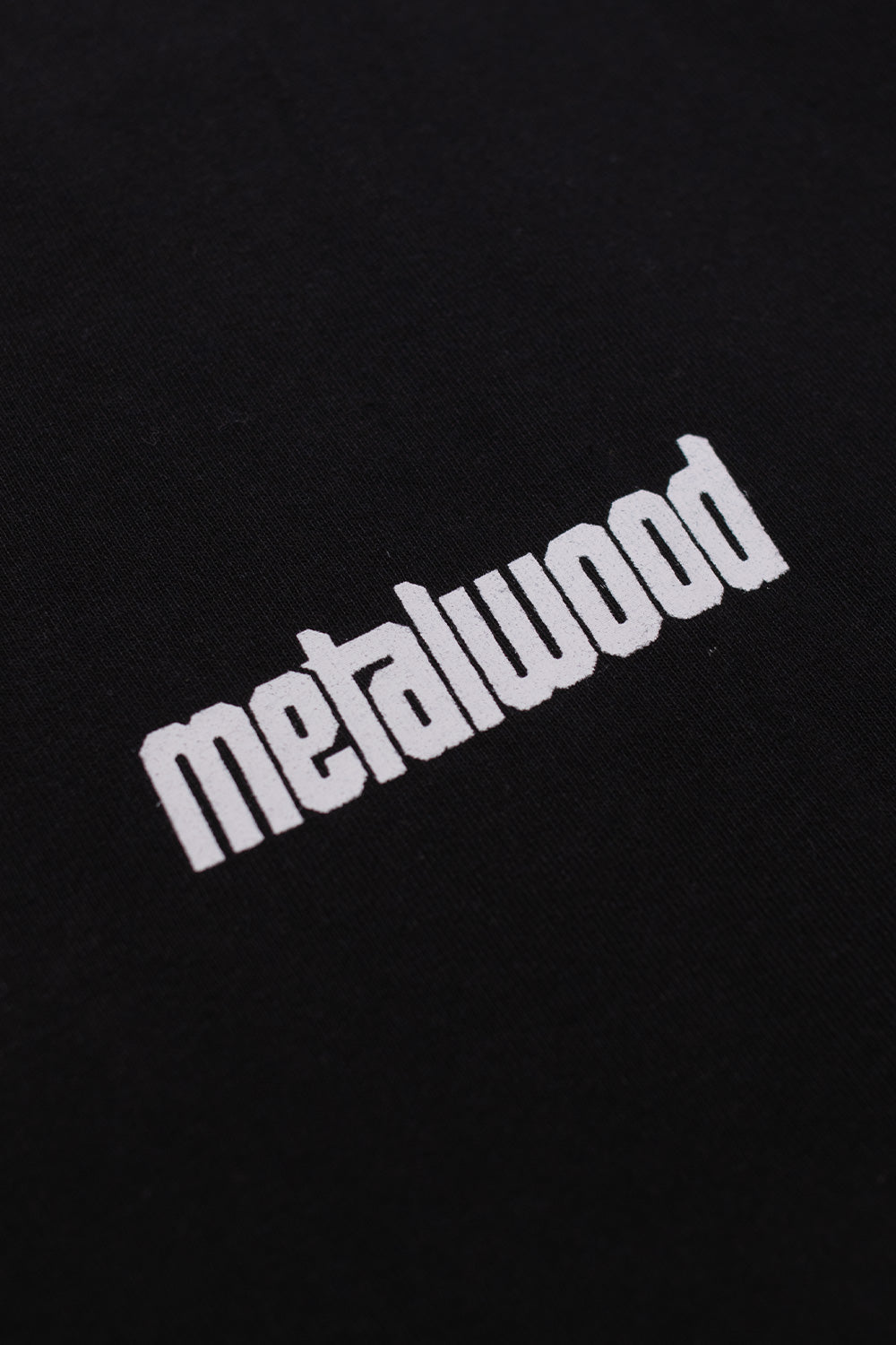 Detailed view of the white Metalwood chest logo print on the Pool T-Shirt Black, highlighting the textured heavy cotton fabric and wide fit construction.