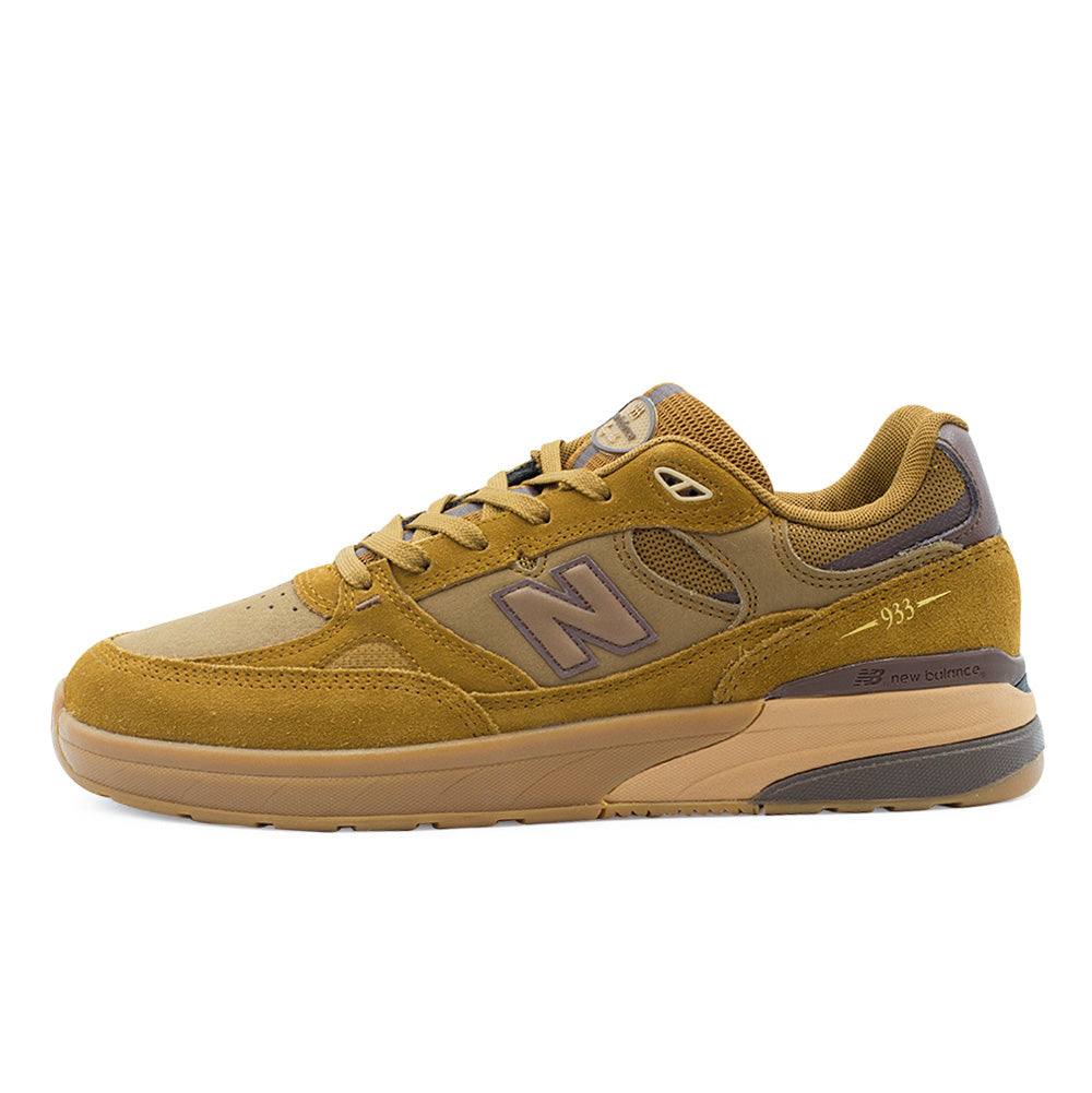 Lateral profile studio view of the New Balance Numeric Andrew Reynolds 933 shoe in Breakfast Tea and Pumpernickel, featuring golden-brown suede overlays across the mudguard, eyestays, and heel, smooth tan leather mid-panels, a signature grey N logo with dark brown outline, a dark brown external heel stability counter, gold-printed 933 branding, and a two-tone gum and brown ABZORB-cushioned midsole.