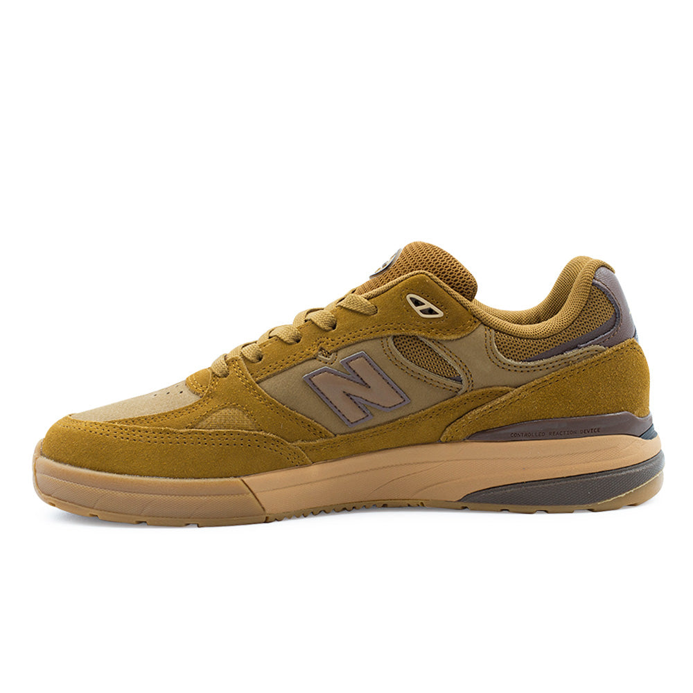 Medial side profile view of the New Balance Numeric Andrew Reynolds 933, showcasing the arch support contouring, clean suede panel stitching, breathable mesh collar inserts, embedded N logo, and embossed Controlled Reaction Device text on the heel cupsole wedge.